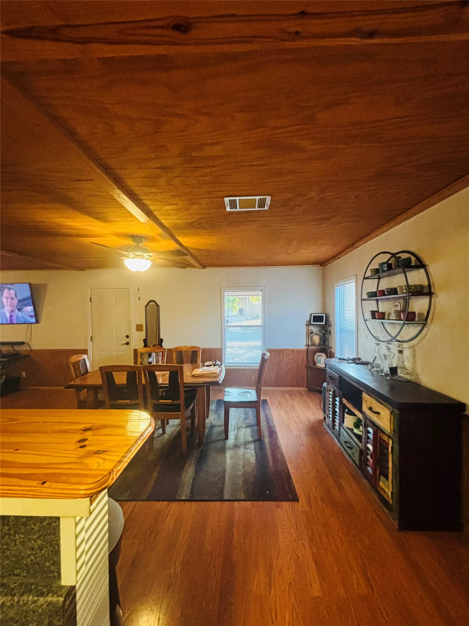 Wood-finish flooring, wood-paneled ceiling with exposed beams, and wood wainscoting