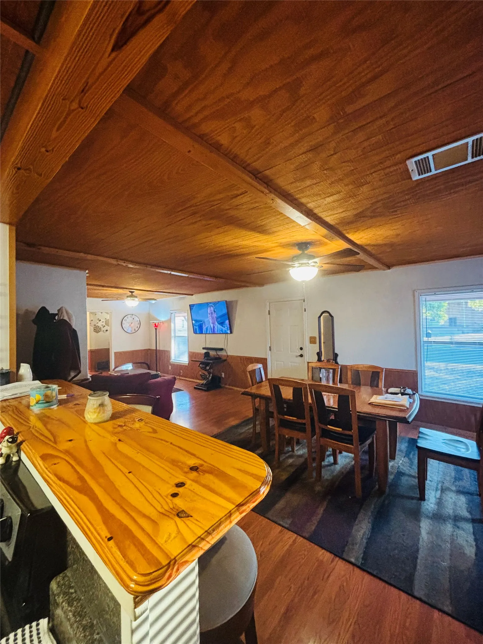 Wood-finish ceiling with exposed beams, wood-finish flooring, and a built-in breakfast bar with wood-finish countertop
