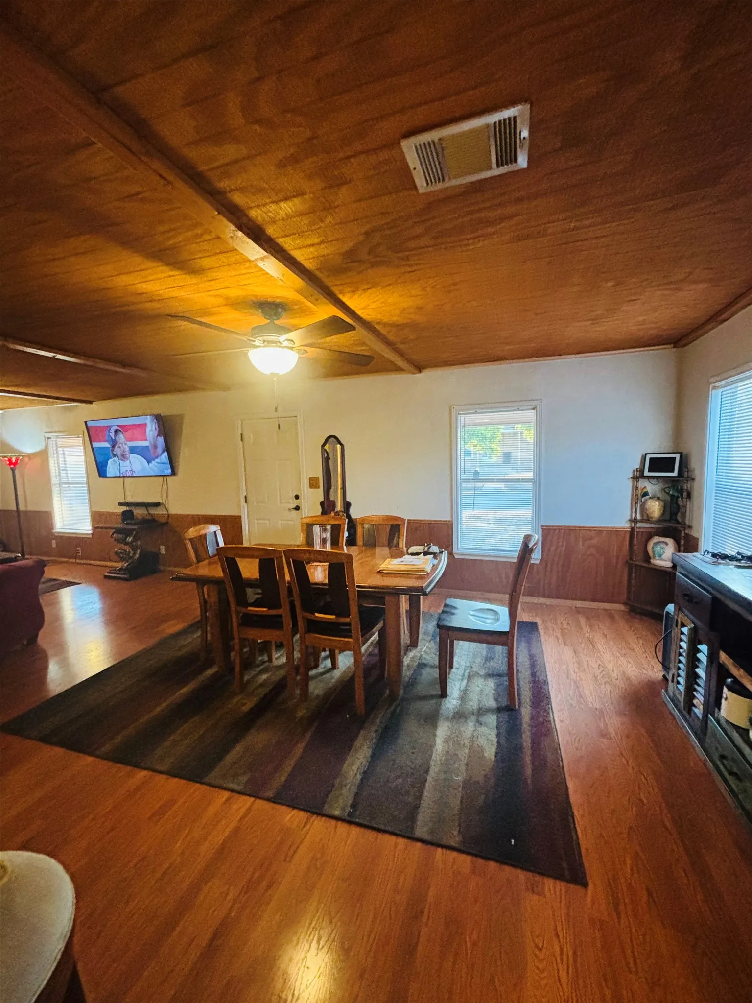 Wood-finish flooring throughout, wood-paneled wainscoting, and a wood-finish ceiling with exposed beams