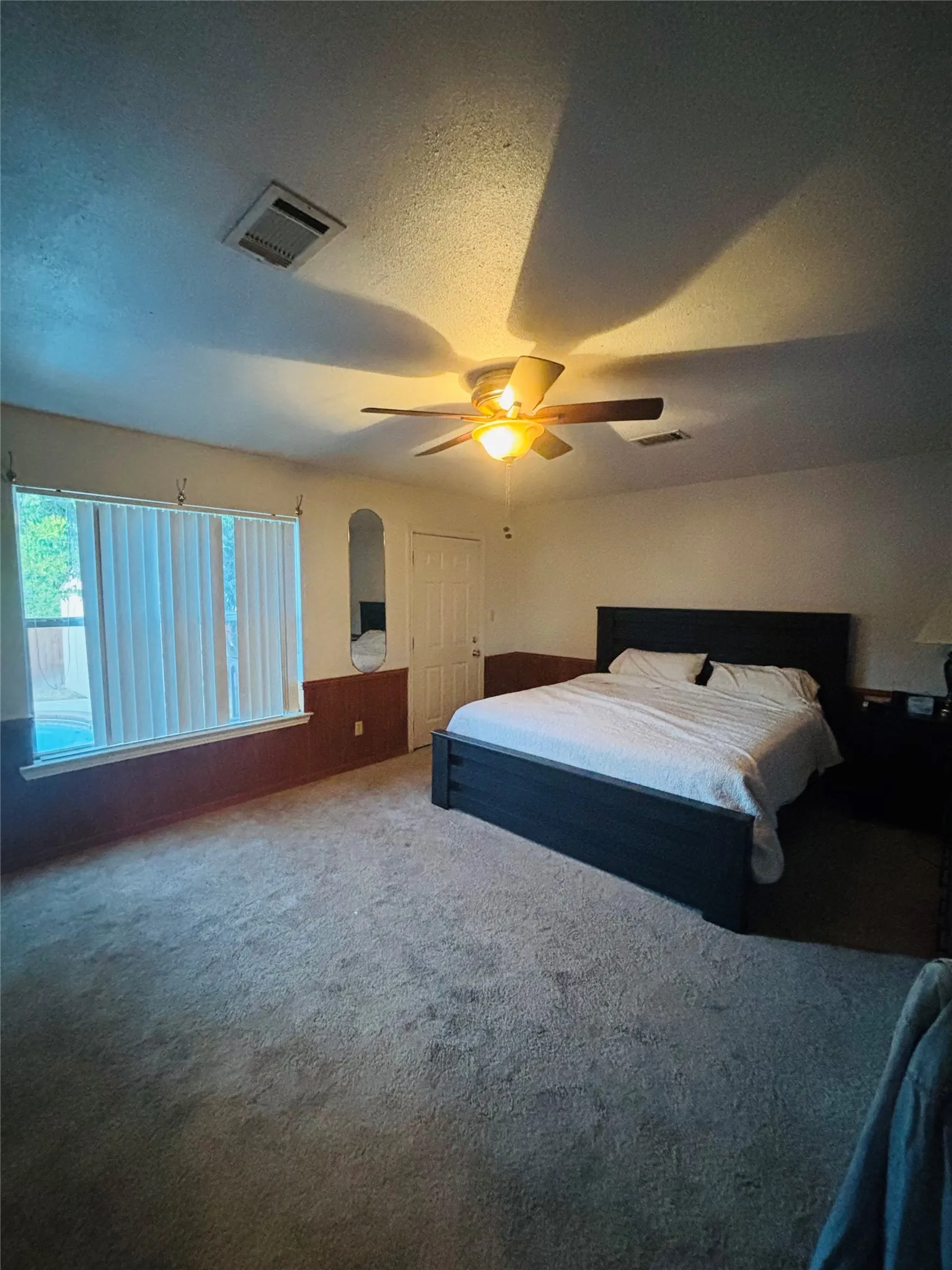 Carpet flooring, ceiling fan with integrated lighting, window with vertical blinds, and a solid core door