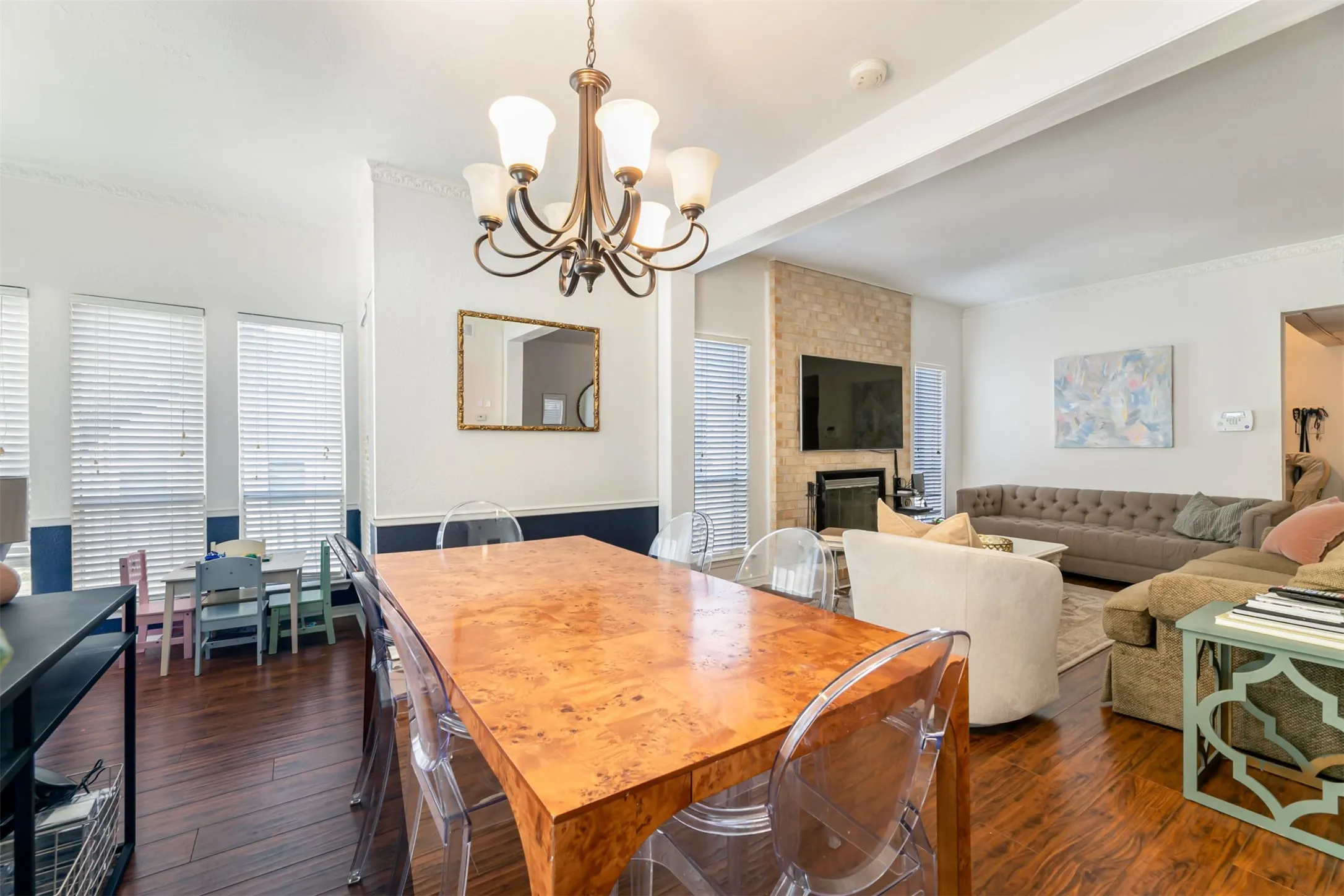 Expansive living area with wood-finish flooring, a chandelier, and a fireplace with a stone surround