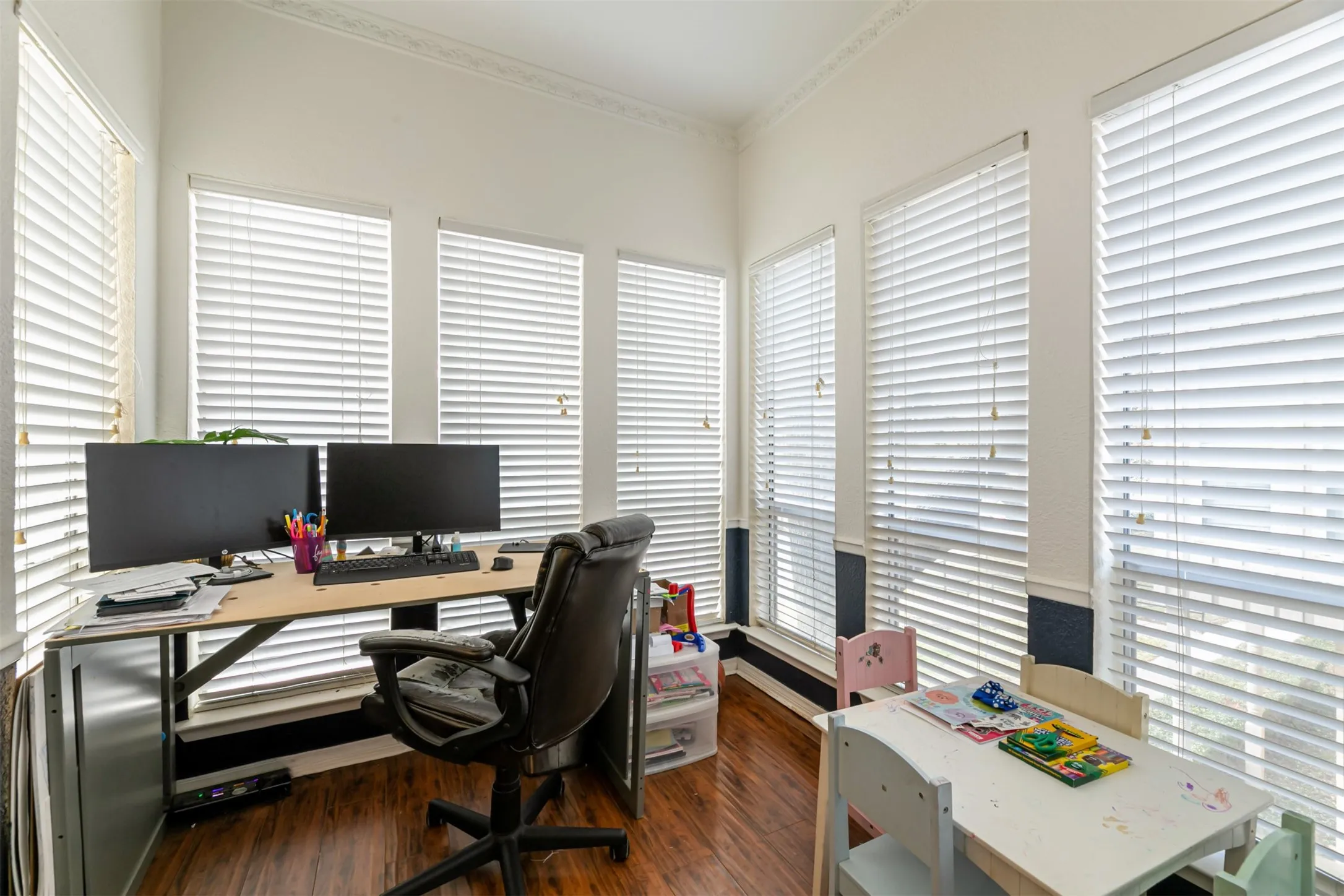 Wood-finish flooring with multiple windows and crown molding