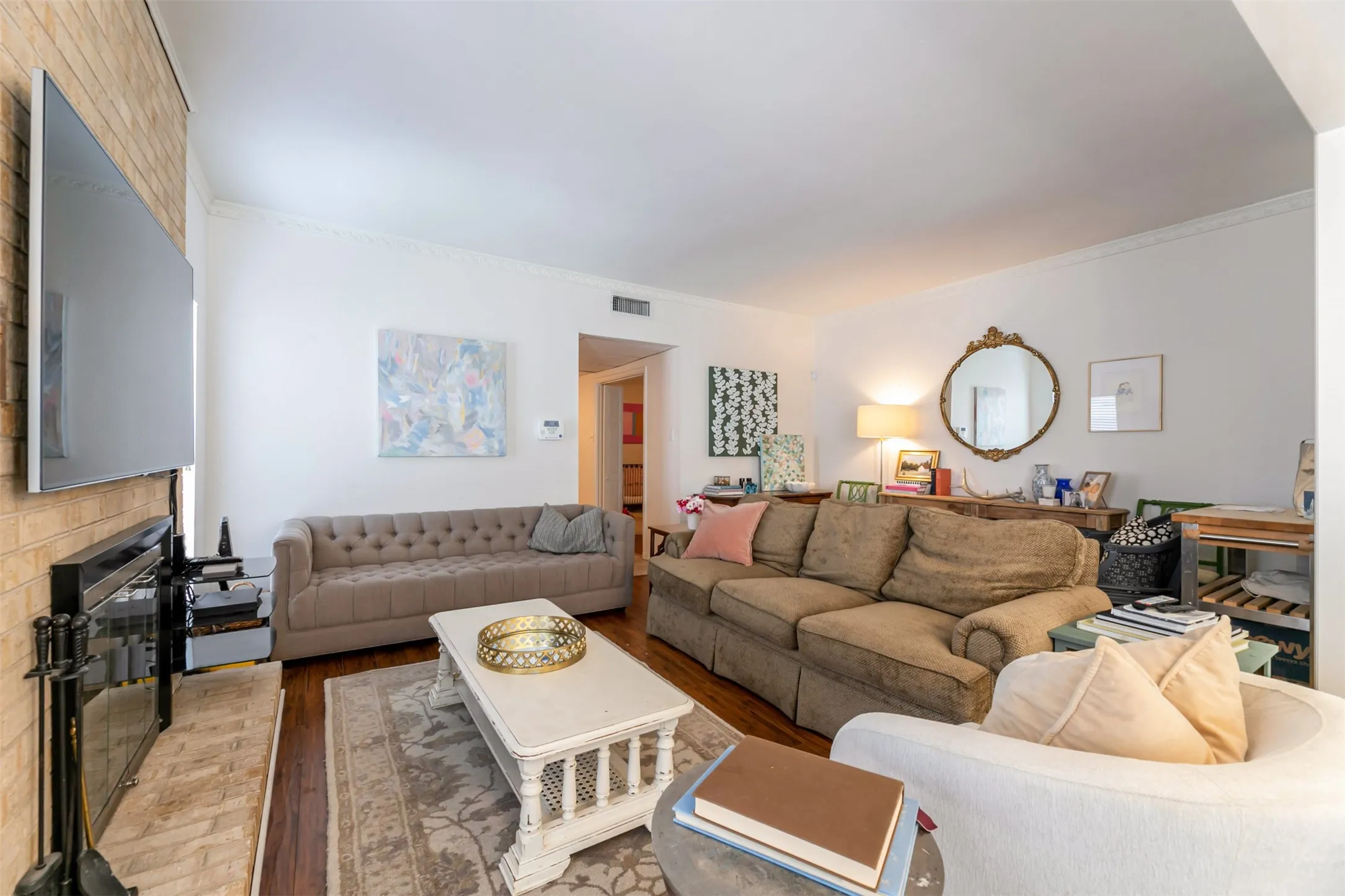 Brick fireplace with hearth, crown molding, and wood-finish flooring