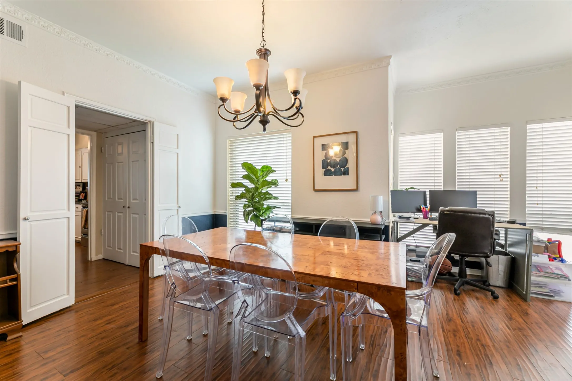 Expansive room with wood-finish flooring, decorative crown molding, and a multi-light chandelier