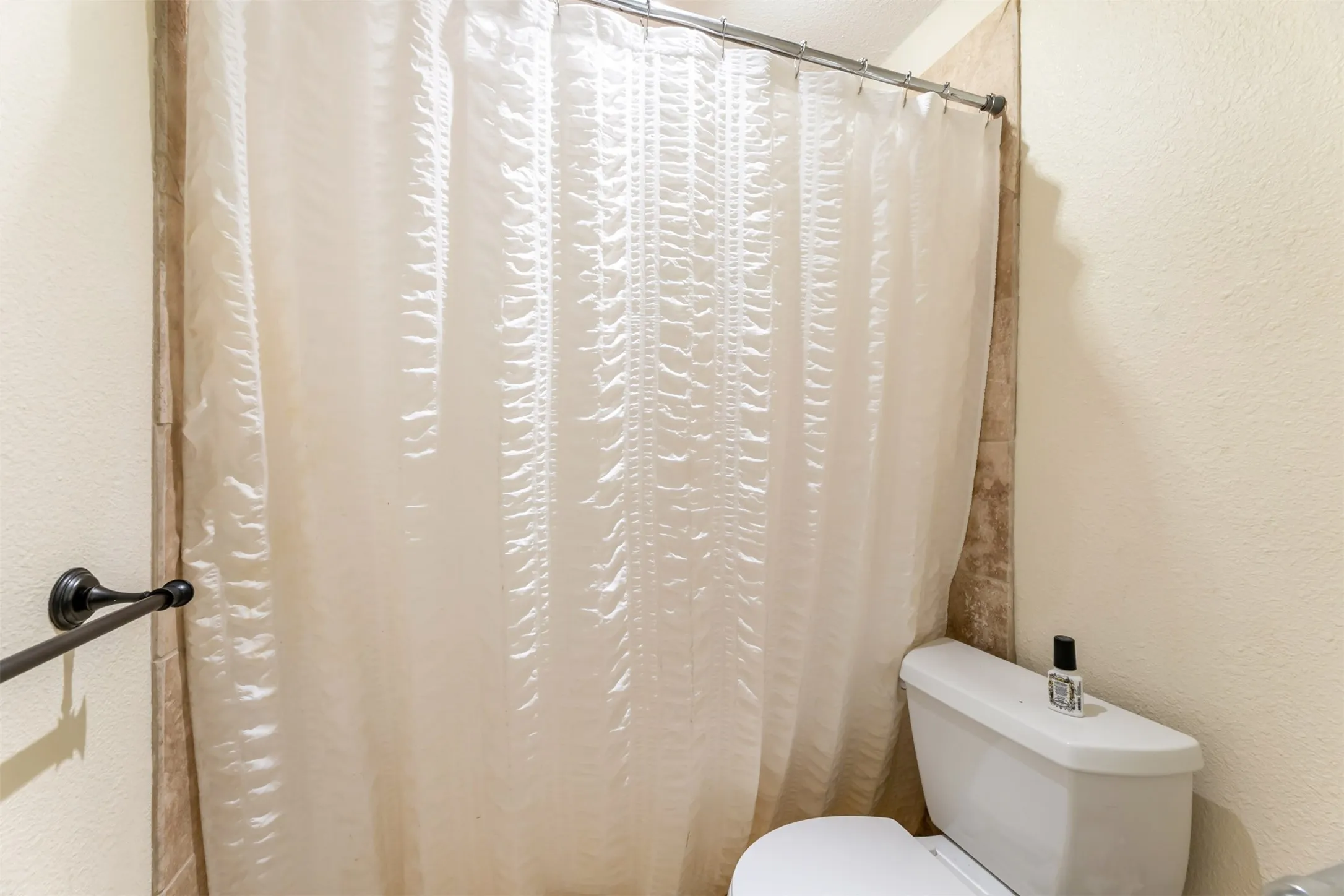 Shower enclosure with tiled walls and a white toilet