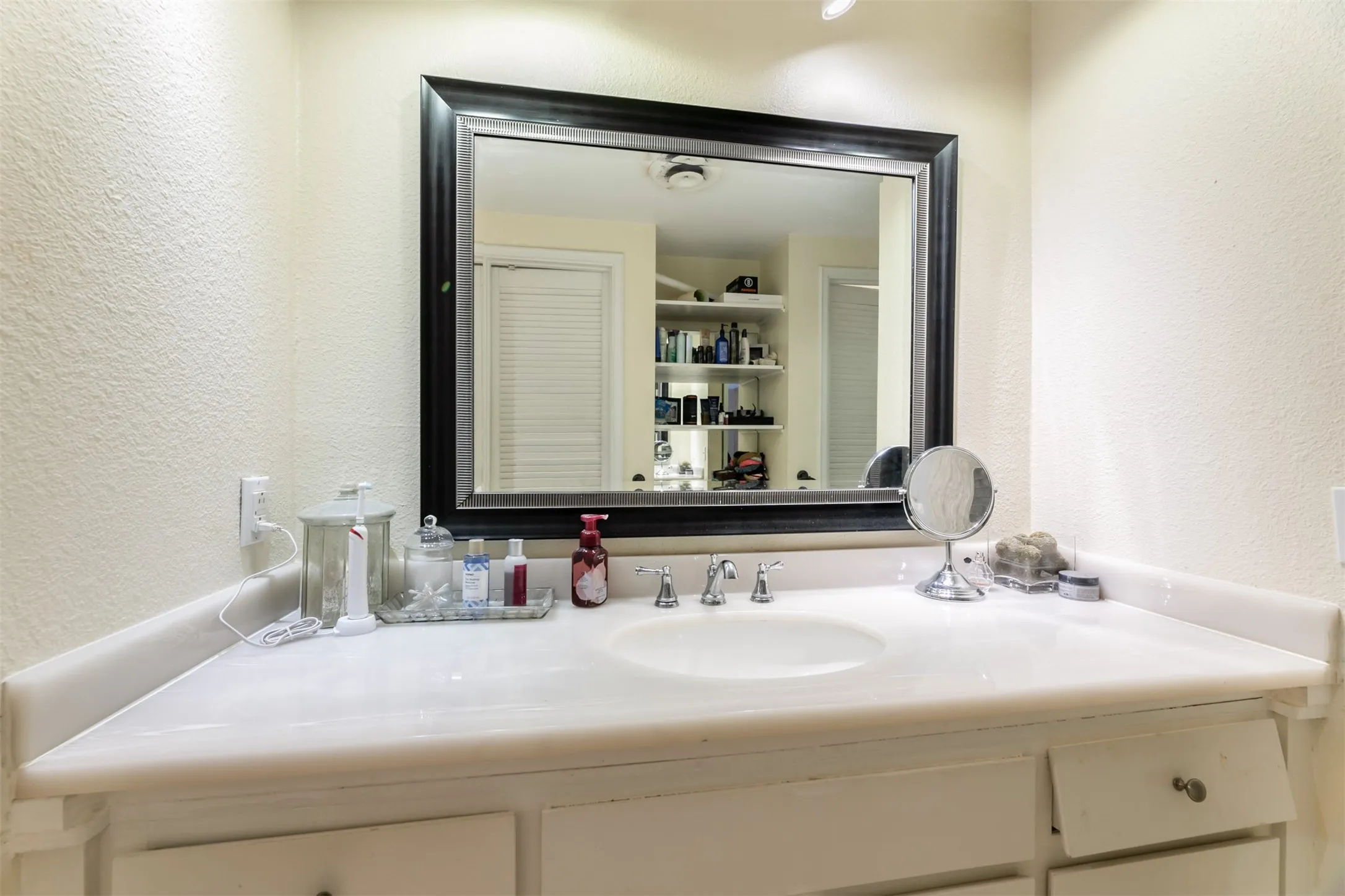 White vanity with integrated sink, framed mirror, and chrome faucet