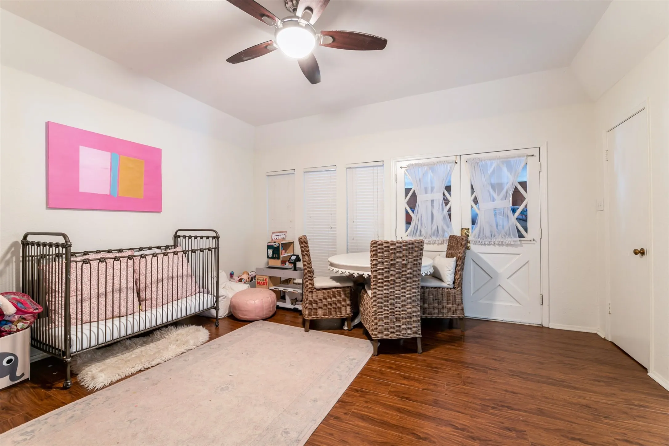 Wood-finish flooring, high ceilings, ceiling fan with integrated lighting, and a white paneled door