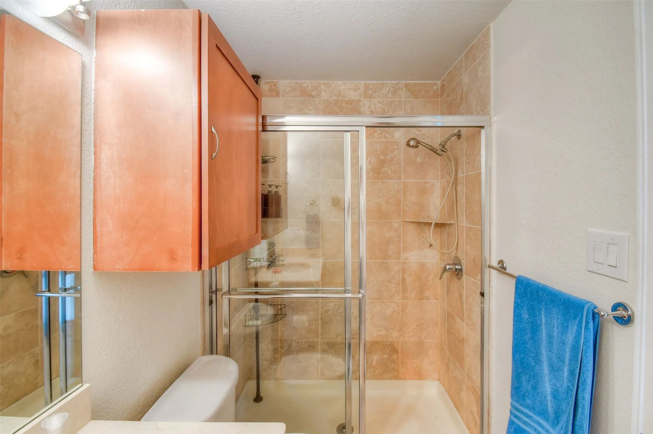 Full bath featuring a textured ceiling, a shower stall, and toilet