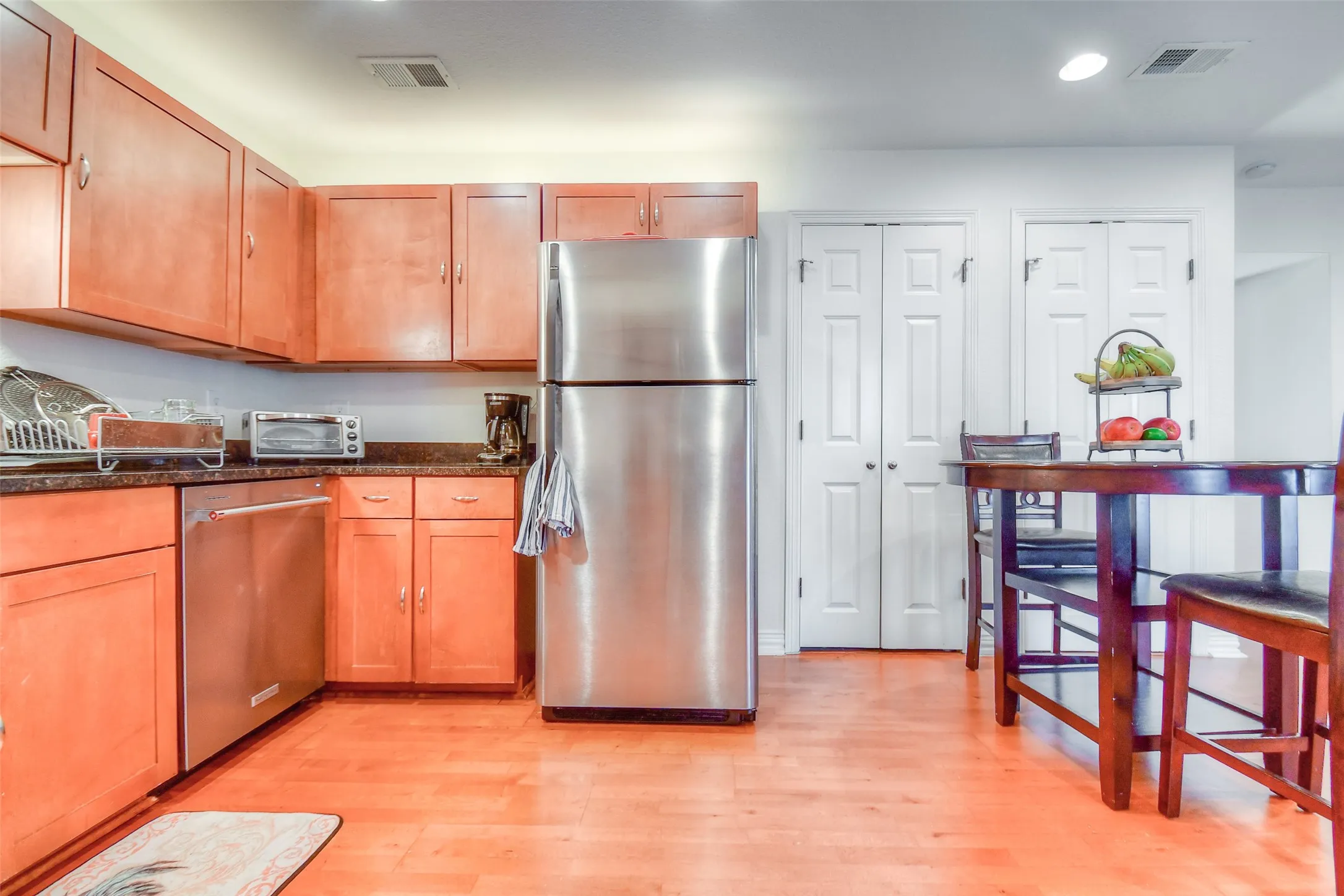 Kitchen with stainless steel appliances, light wood-style flooring, visible vents, and a toaster