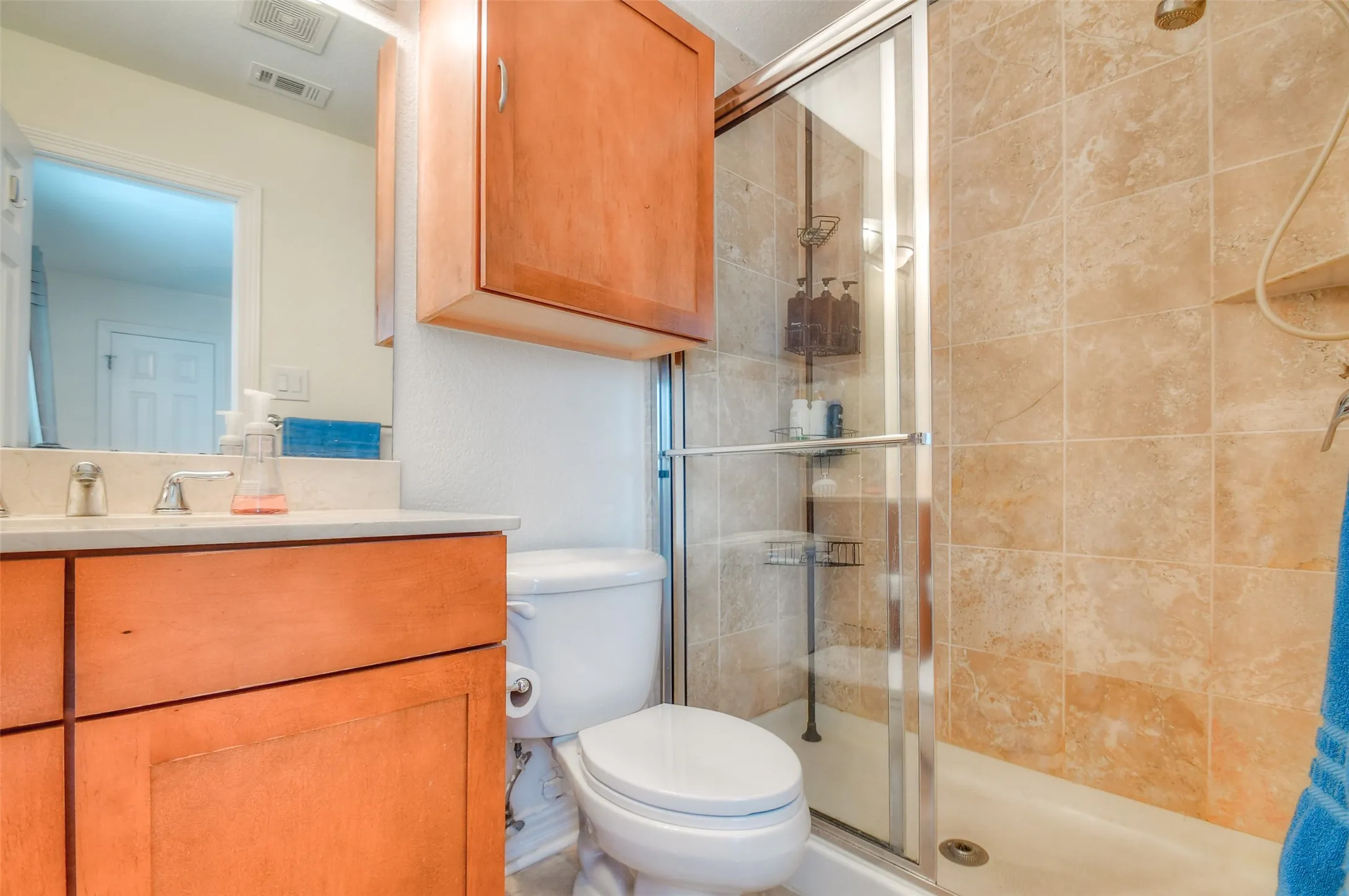 Full bath featuring toilet, a stall shower, vanity, and visible vents