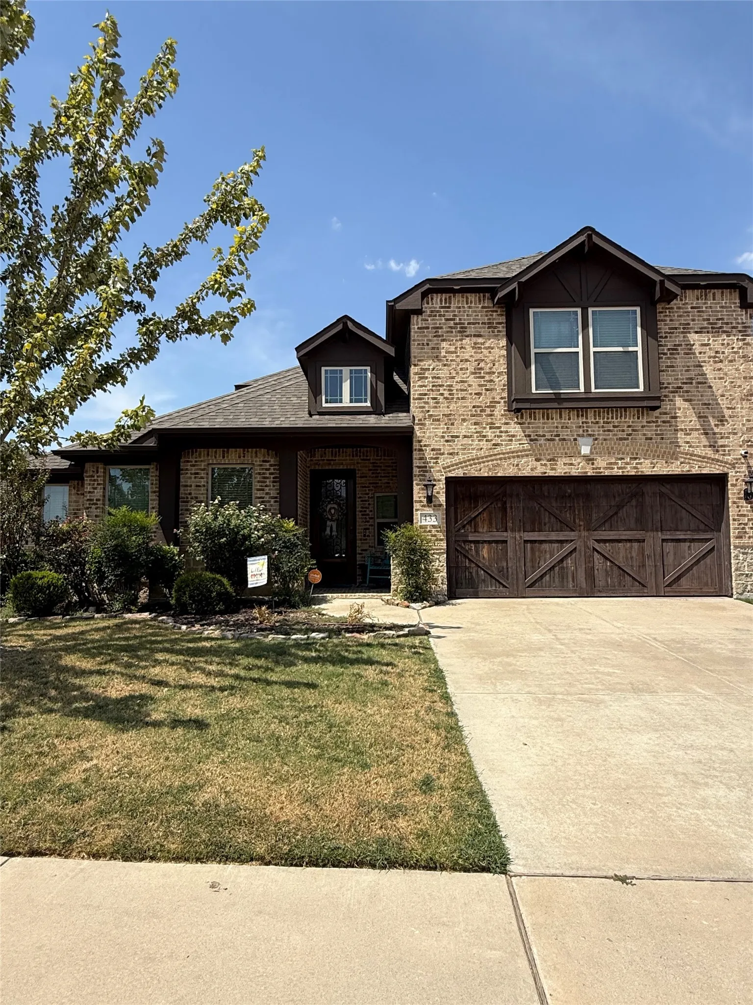 Brick facade with dark trim accents, dormer windows, and a concrete driveway