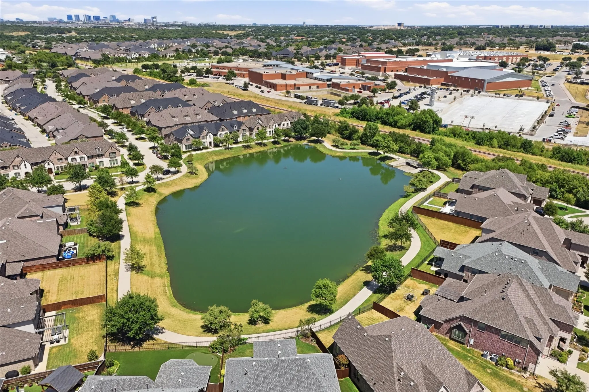 Community featuring a central pond, surrounding walking path, and varied residential architecture