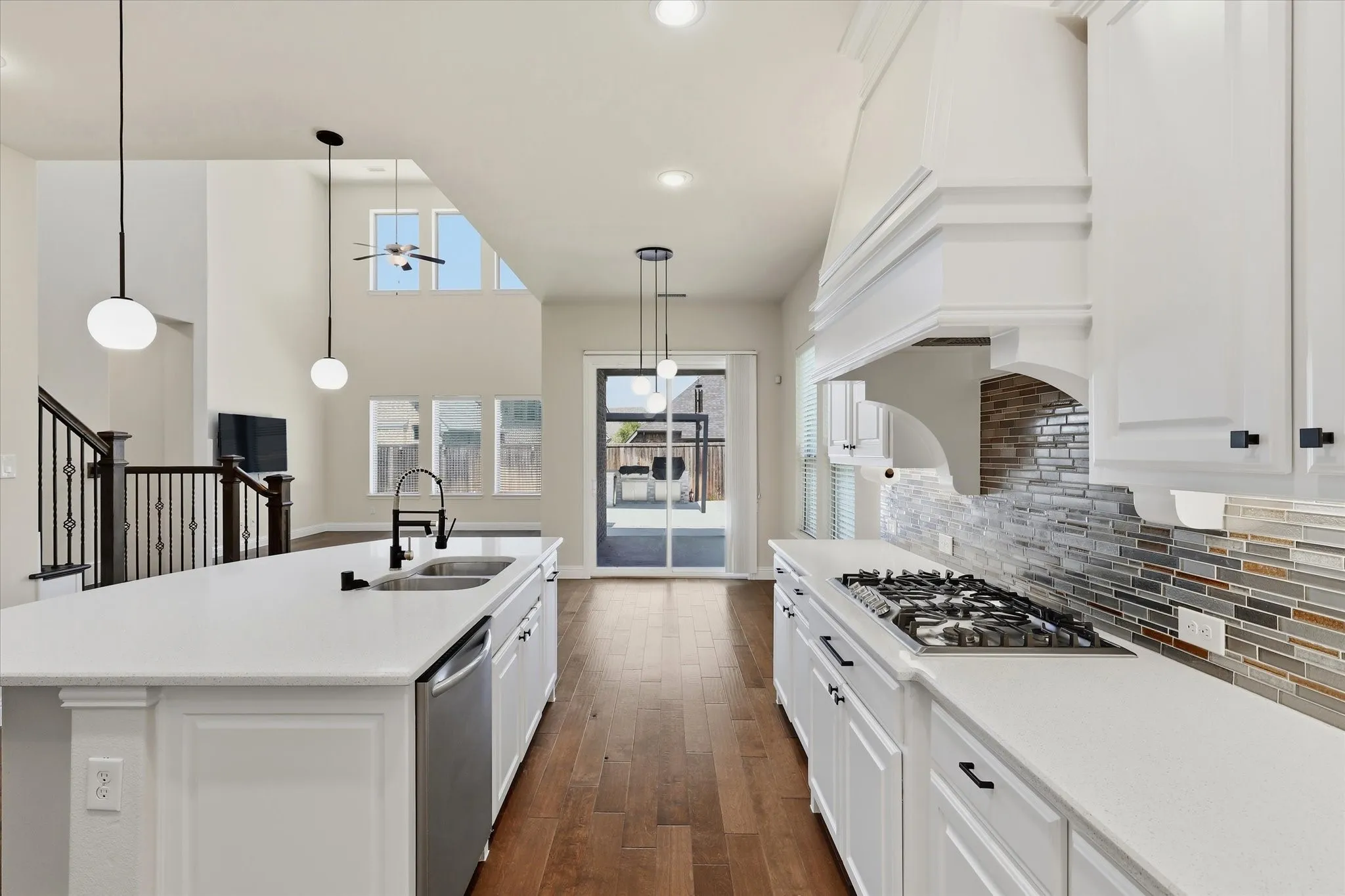 Gourmet kitchen with white cabinetry, gas cooktop, stone countertops, and tile backsplash