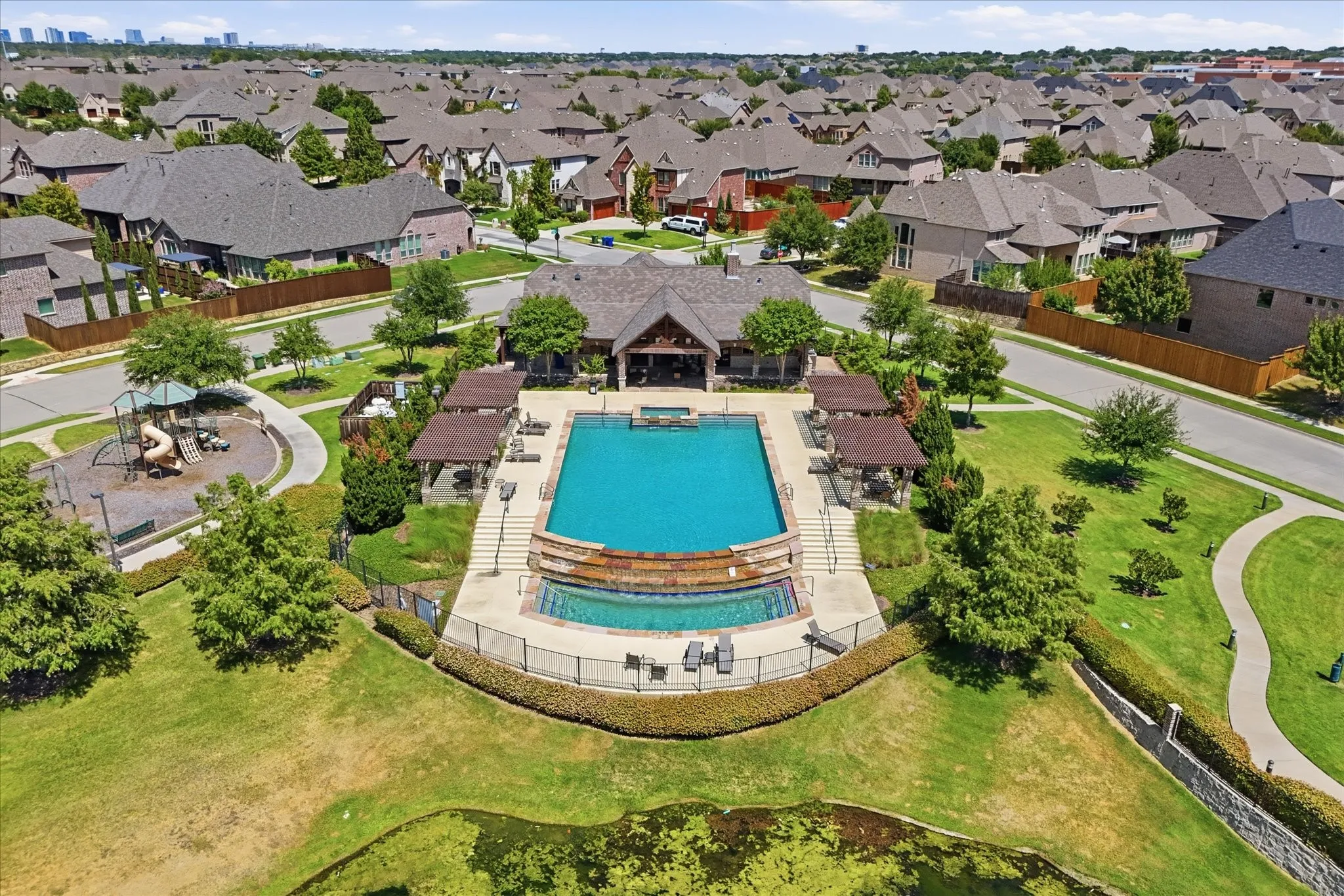 Community swimming pool with an integrated spa, surrounding pergolas, and a clubhouse