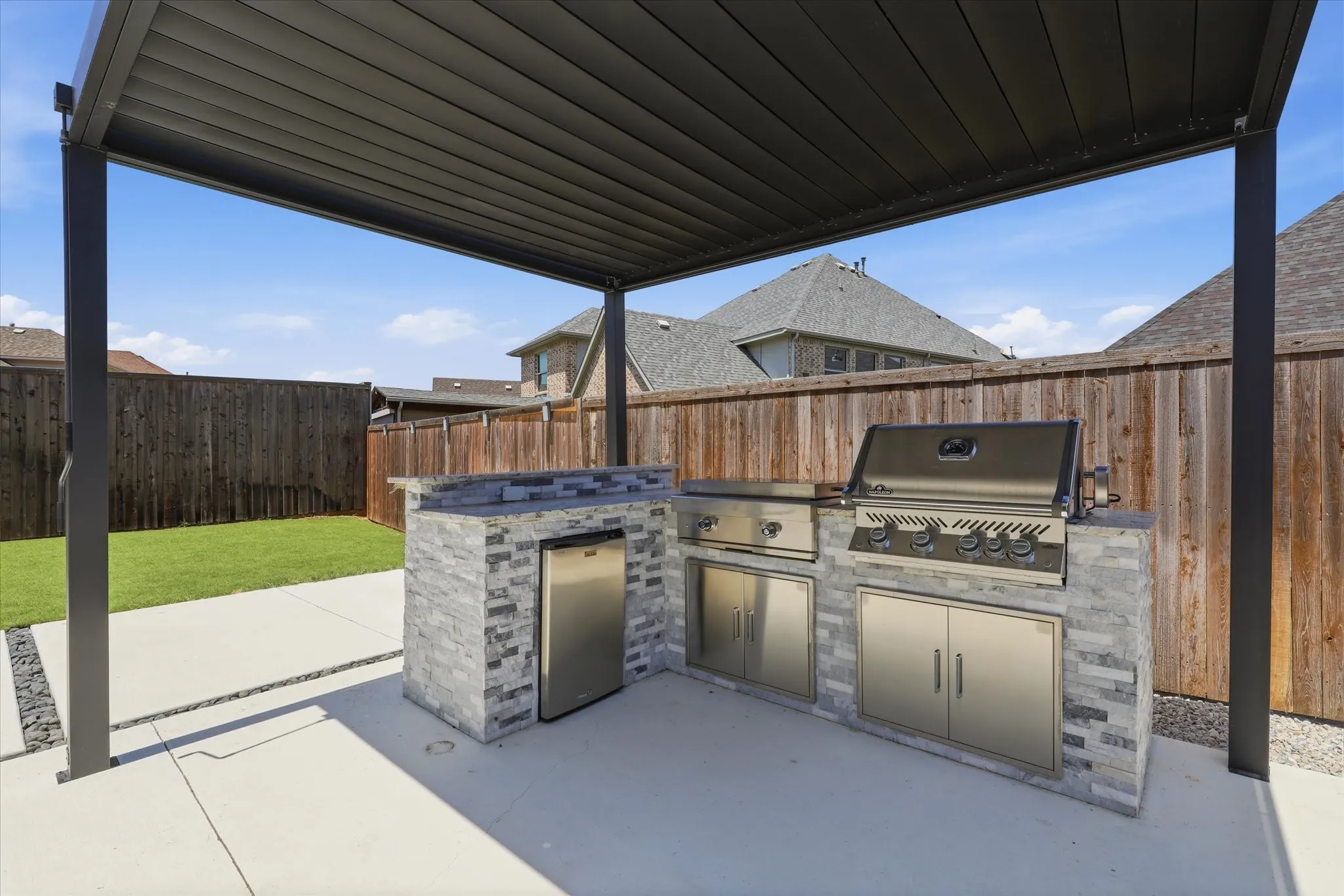 Outdoor kitchen with a built-in grill, stainless steel appliances, and stacked stone veneer
