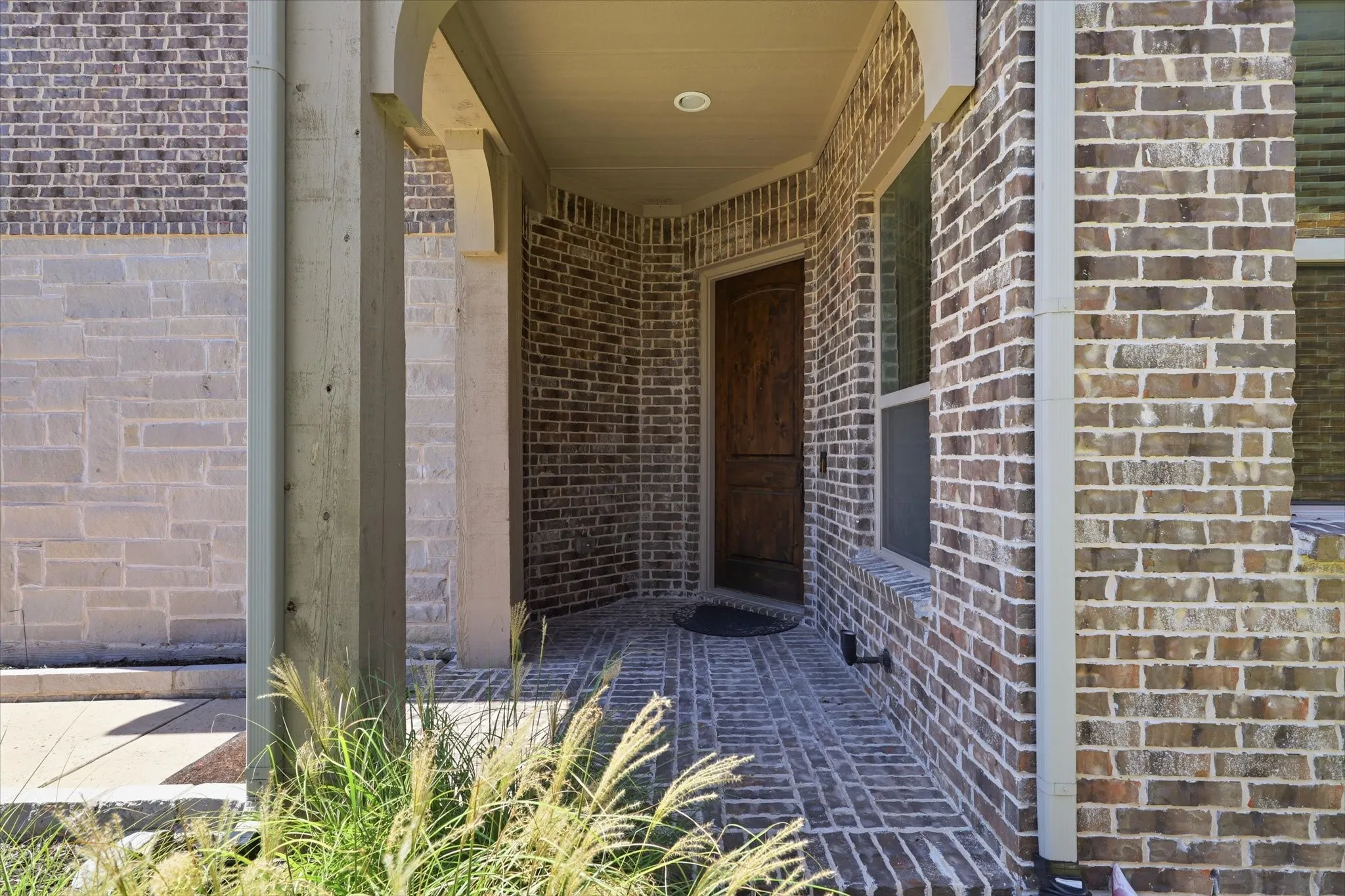 Covered entry featuring a wood-panel door with brick and stone exterior.