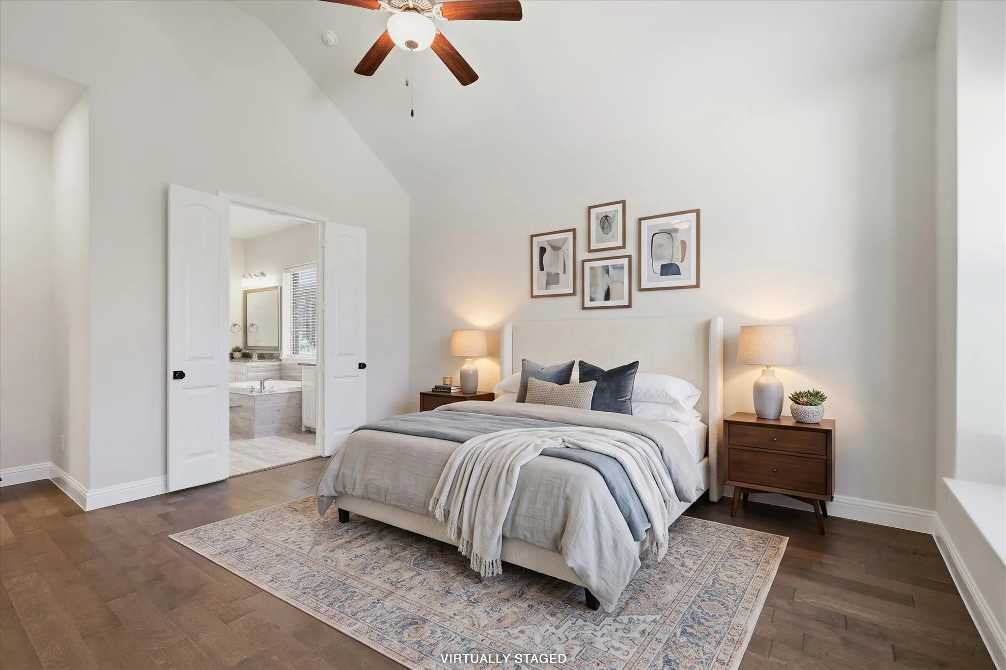 Primary bedroom suite featuring a vaulted ceiling with ceiling fan, wood flooring, and an ensuite bathroom accessible through French doors
