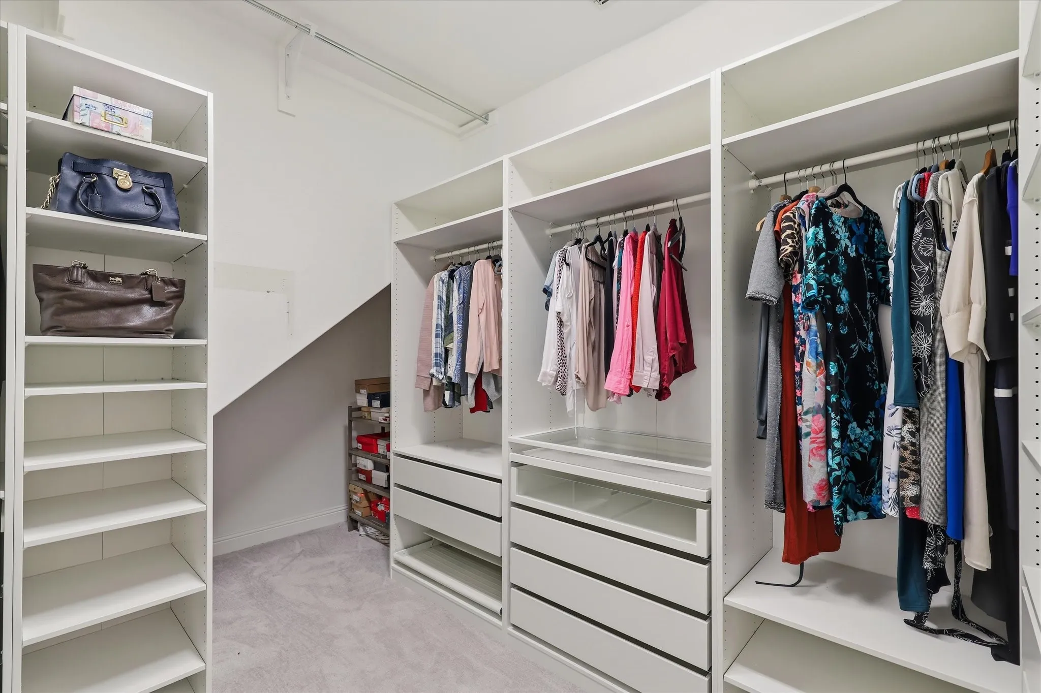 Primary bathroom Custom closet system featuring multiple shelves, hanging rods, and built-in drawers
