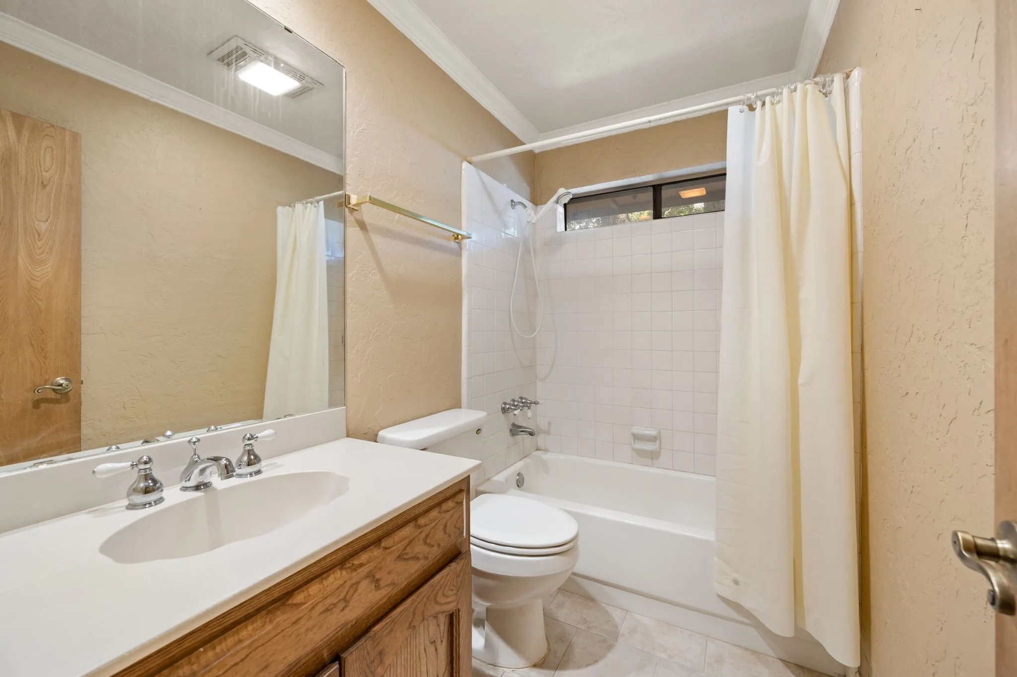 White vanity with a single basin, chrome fixtures, and wood-finish cabinetry