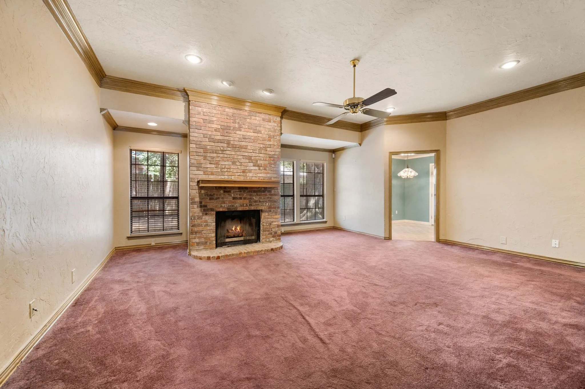 Living area featuring a brick fireplace with a wood mantle, recessed lighting, ceiling fan, and large windows
