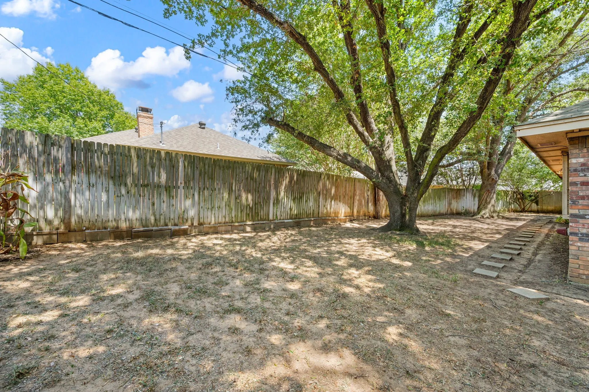 Private backyard featuring mature trees, a wood privacy fence, and brick exterior siding