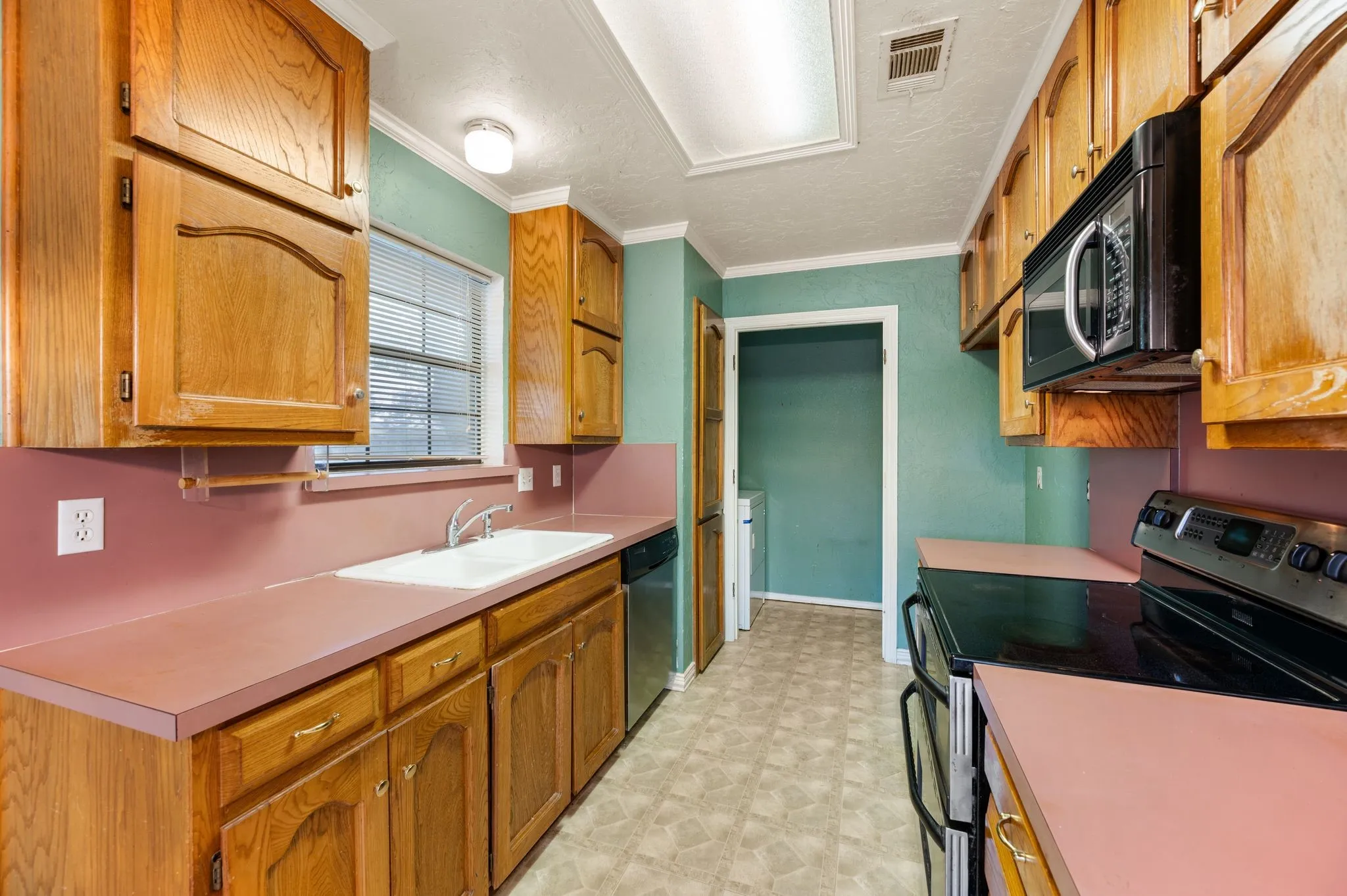 Kitchen featuring wood cabinetry, laminate countertops, built-in microwave, and an electric range