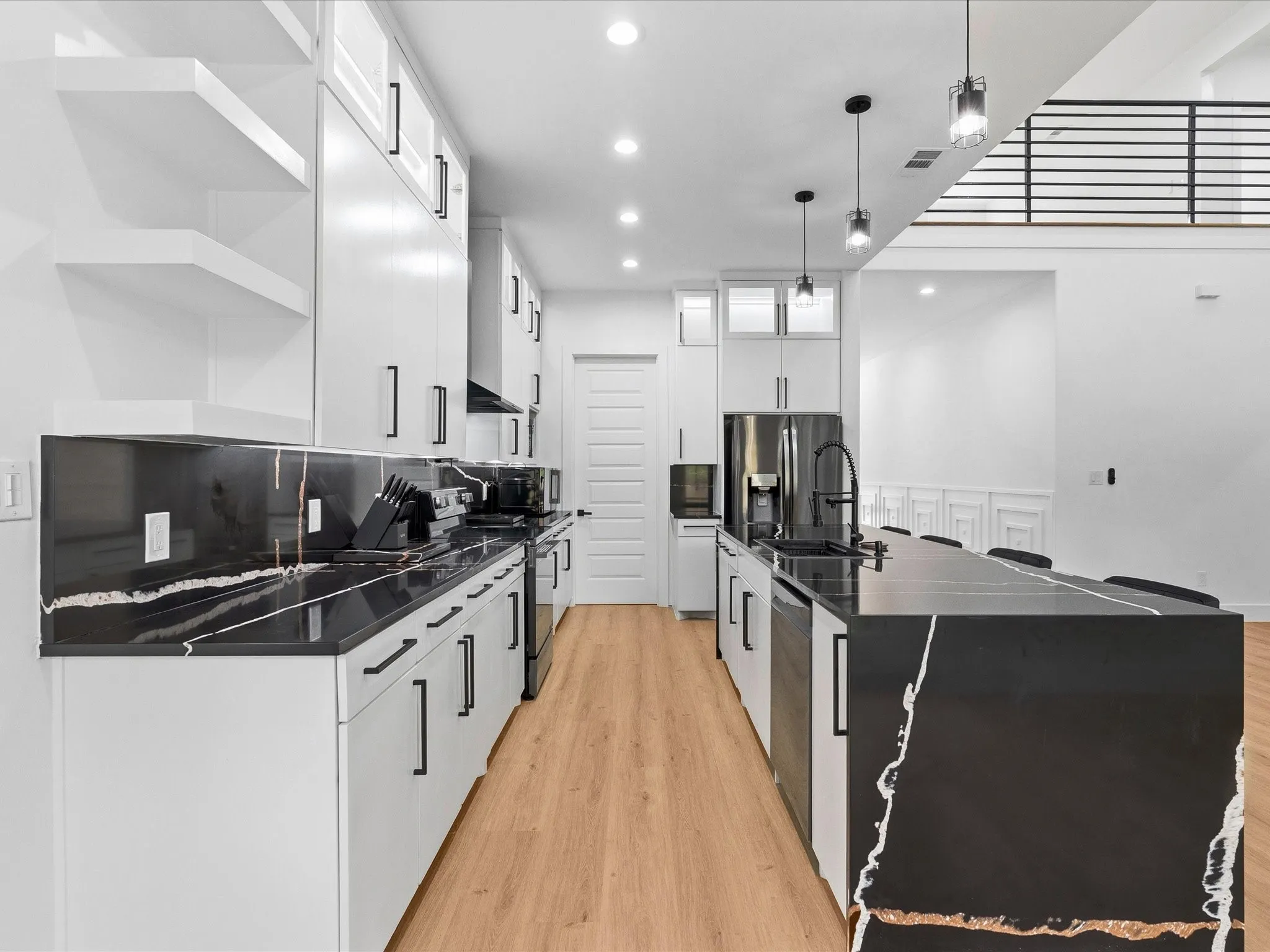 Kitchen featuring black countertops with white and gold veining, white cabinetry, wood-finish flooring, recessed lighting, and a kitchen island with pendant lighting