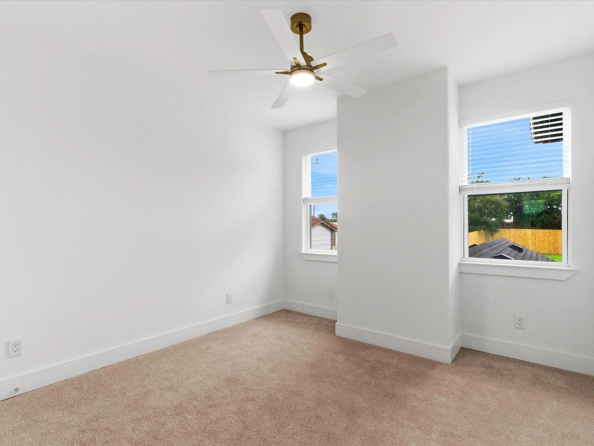 Recessed wall partition, ceiling fan with light fixture, two windows, and carpet flooring