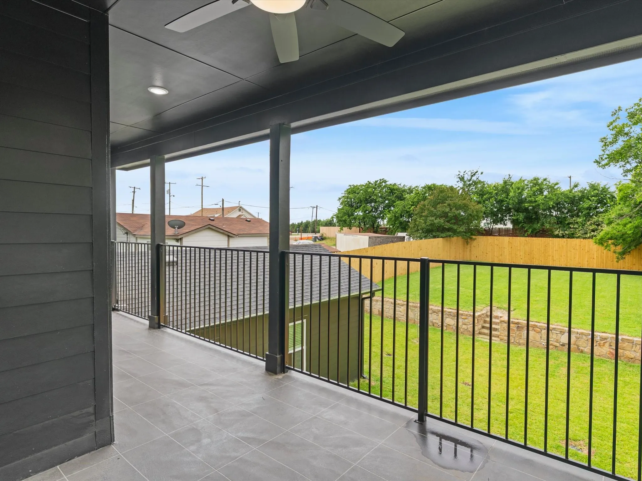 Covered balcony featuring a ceiling fan, recessed lighting, tile flooring, and black metal railing