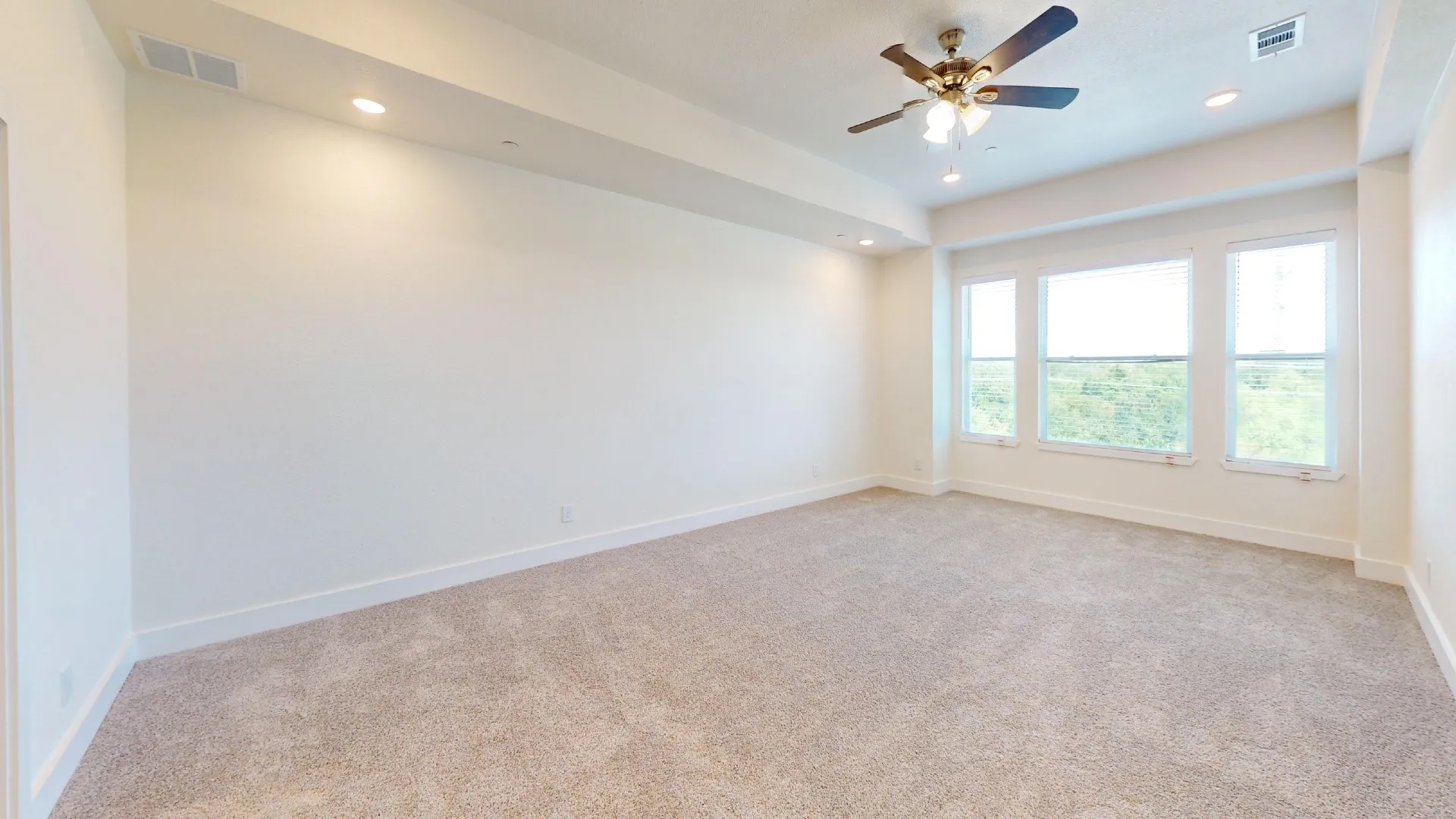 Expansive room featuring plush carpet flooring, recessed lighting, a ceiling fan, and multiple windows