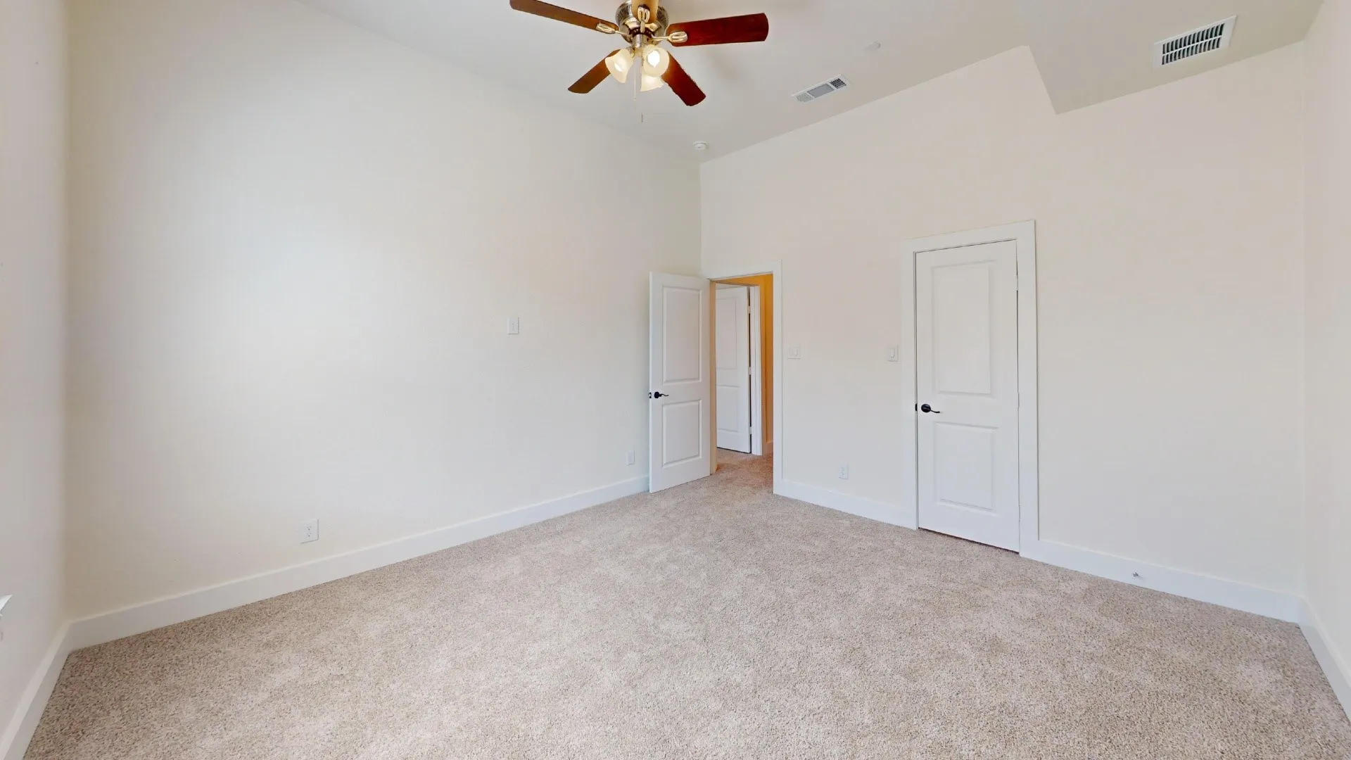 Vaulted ceiling, ceiling fan, neutral wall paint, two interior doors, and carpet flooring