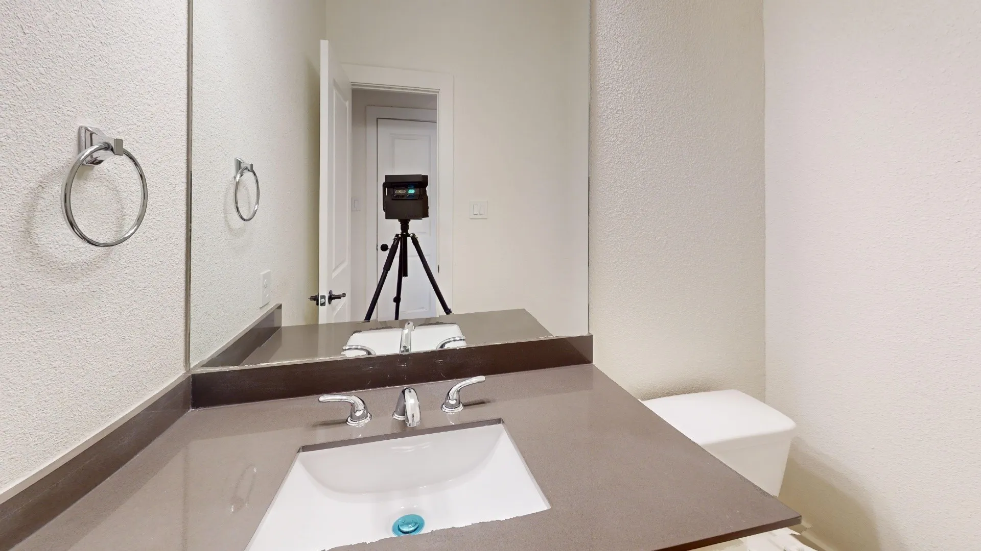 Vanity with an integrated sink, polished chrome faucet, and expansive wall-mounted mirror