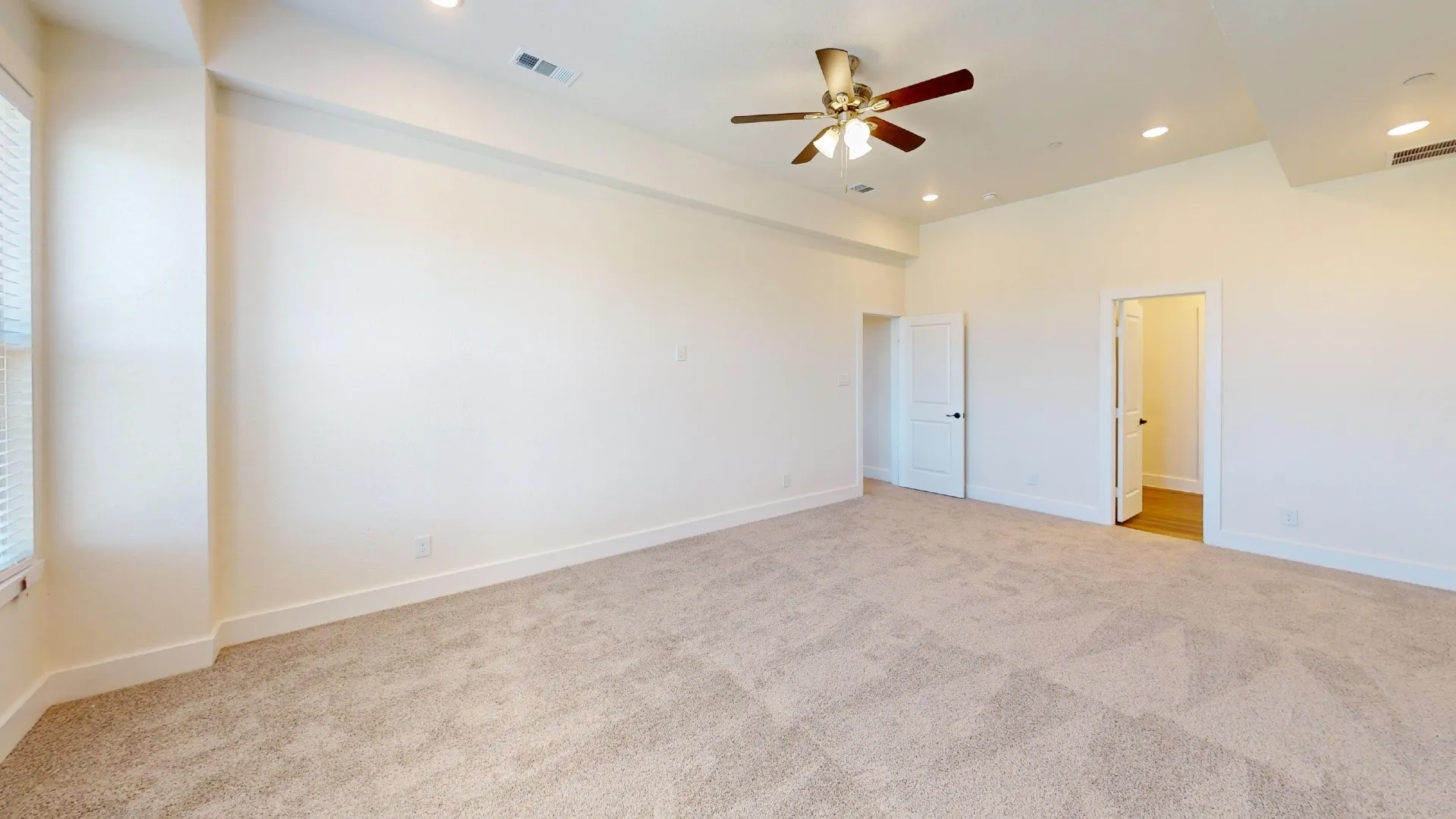Spacious room featuring neutral carpeting, recessed lighting, and a ceiling fan
