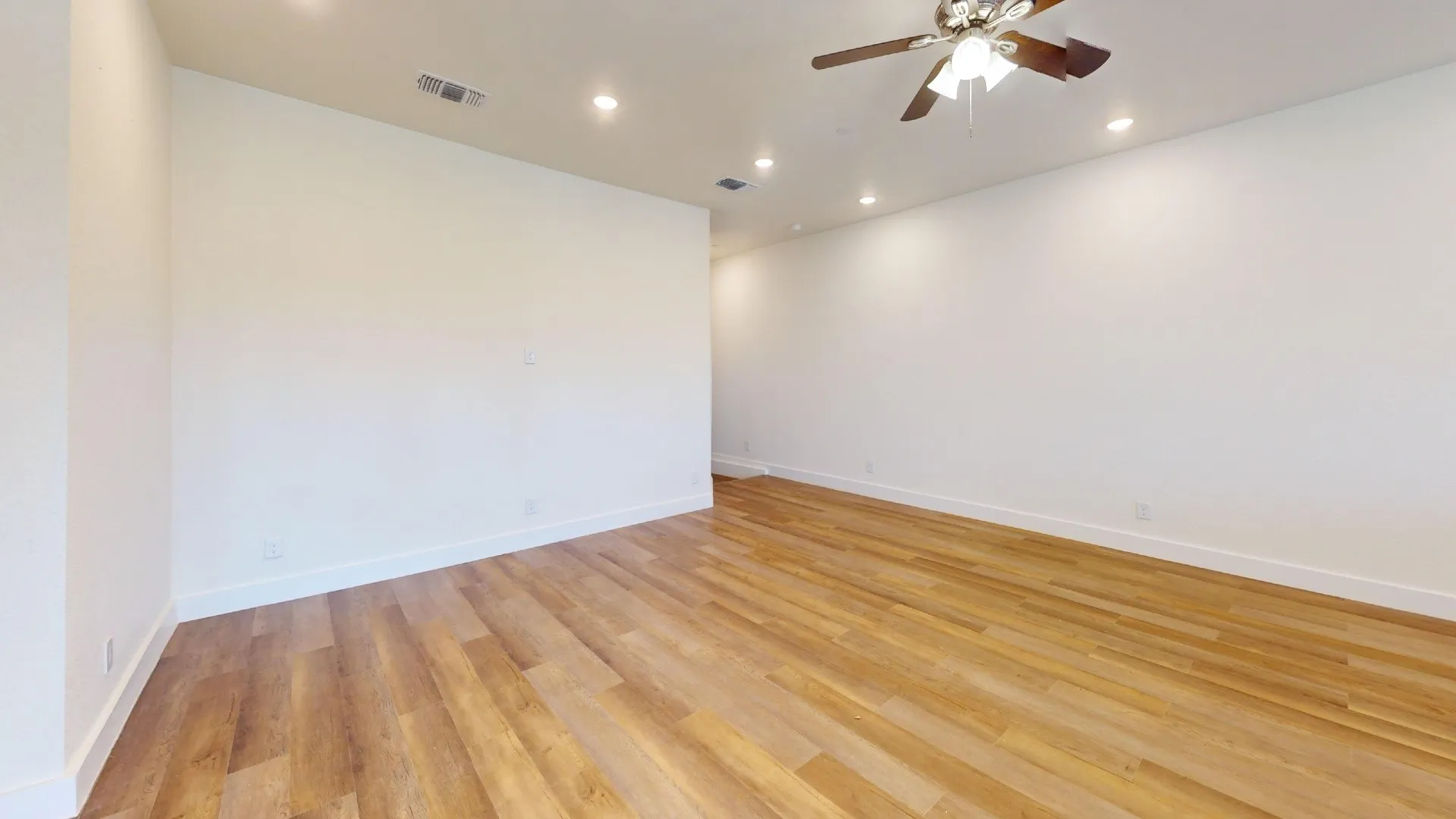 Expansive room featuring wood-finish flooring, recessed lighting, and a ceiling fan