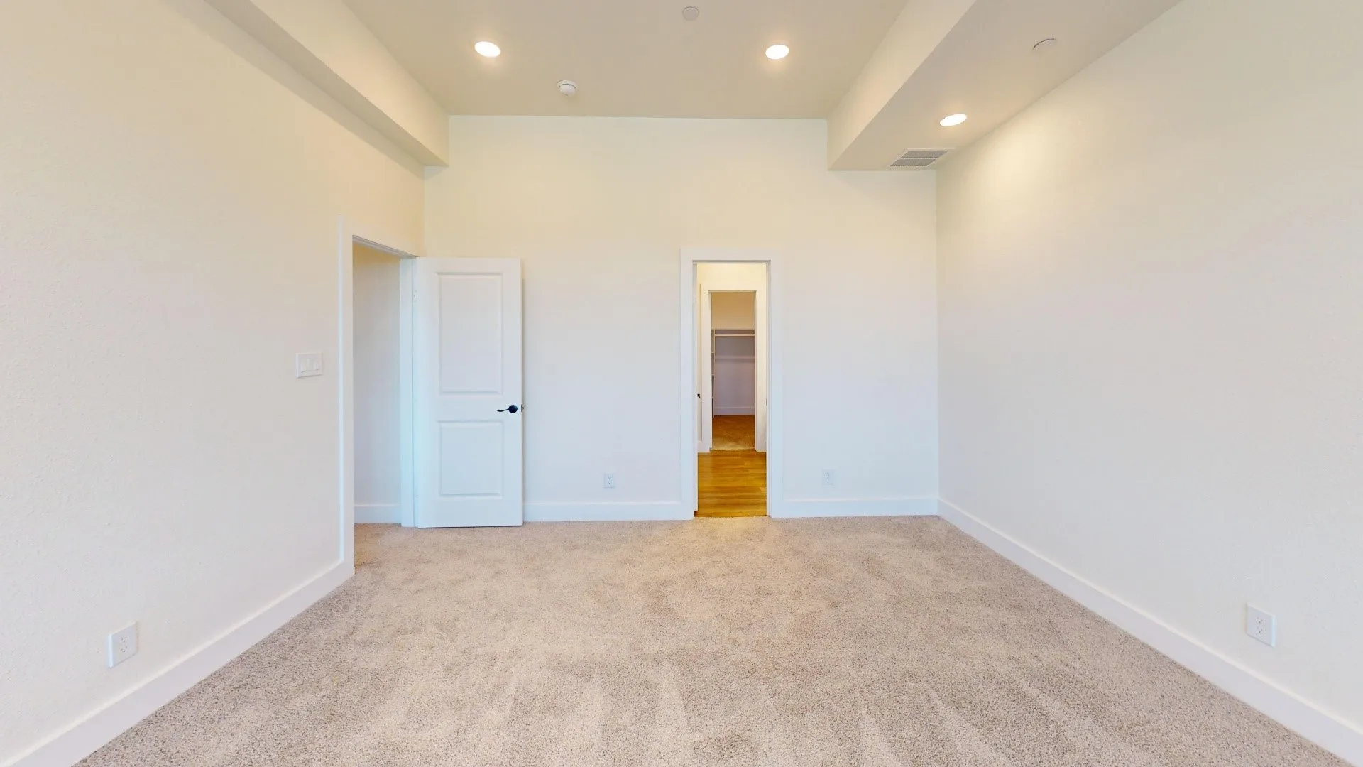 Plush carpeting, recessed lighting, and a neutral color palette
