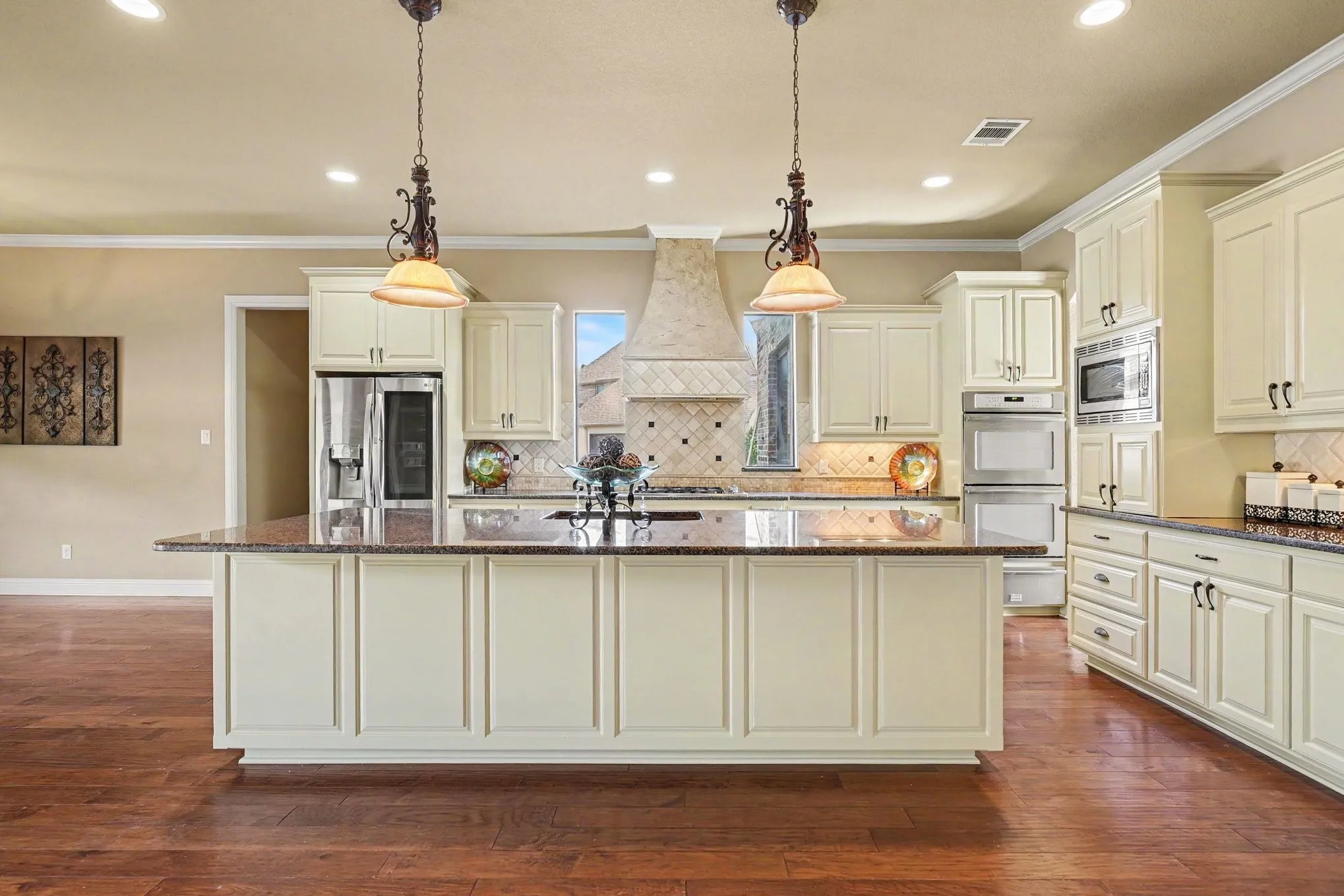 Gourmet kitchen with wood-finish flooring, custom cabinetry, large central island with countertop, and stainless steel appliances