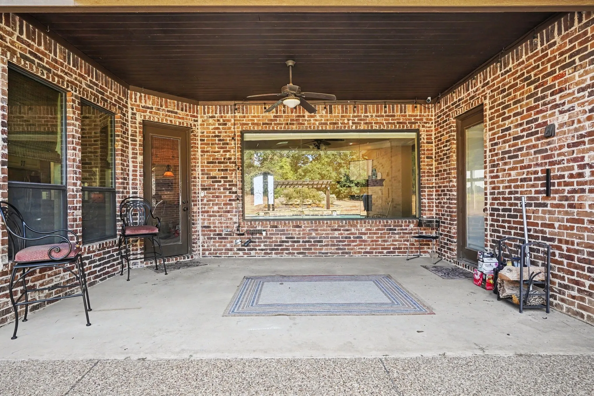Expansive covered patio featuring brick walls, a concrete floor, and a ceiling fan