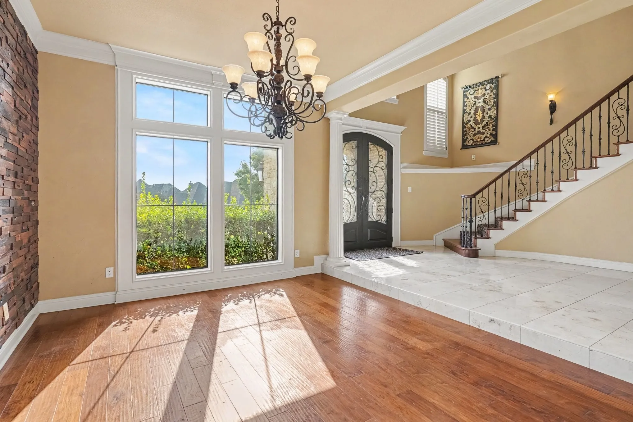 Hardwood flooring, tiled entryway, wrought iron staircase, decorative front entry door, and large picture windows