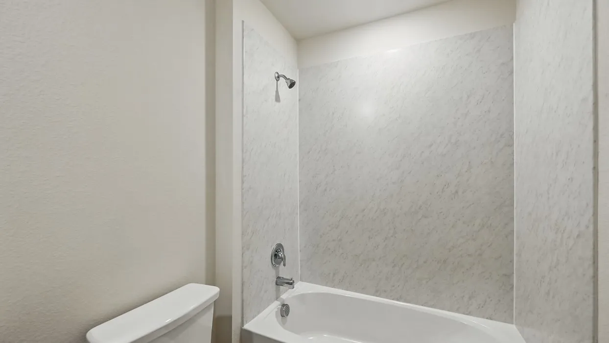 White ceramic toilet with a matching bathtub and shower surround, featuring chrome fixtures