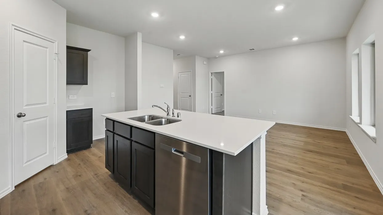 Kitchen island with a double basin sink, stainless steel dishwasher, and dark wood-finish cabinetry