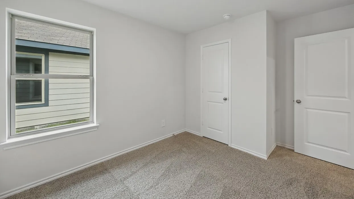 Neutral-toned carpeting, white interior doors, and a window with white trim