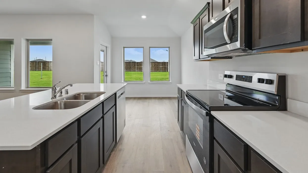 Kitchen featuring white countertops, stainless steel appliances, dark wood-finish cabinetry, a double basin sink, and wood-finish flooring