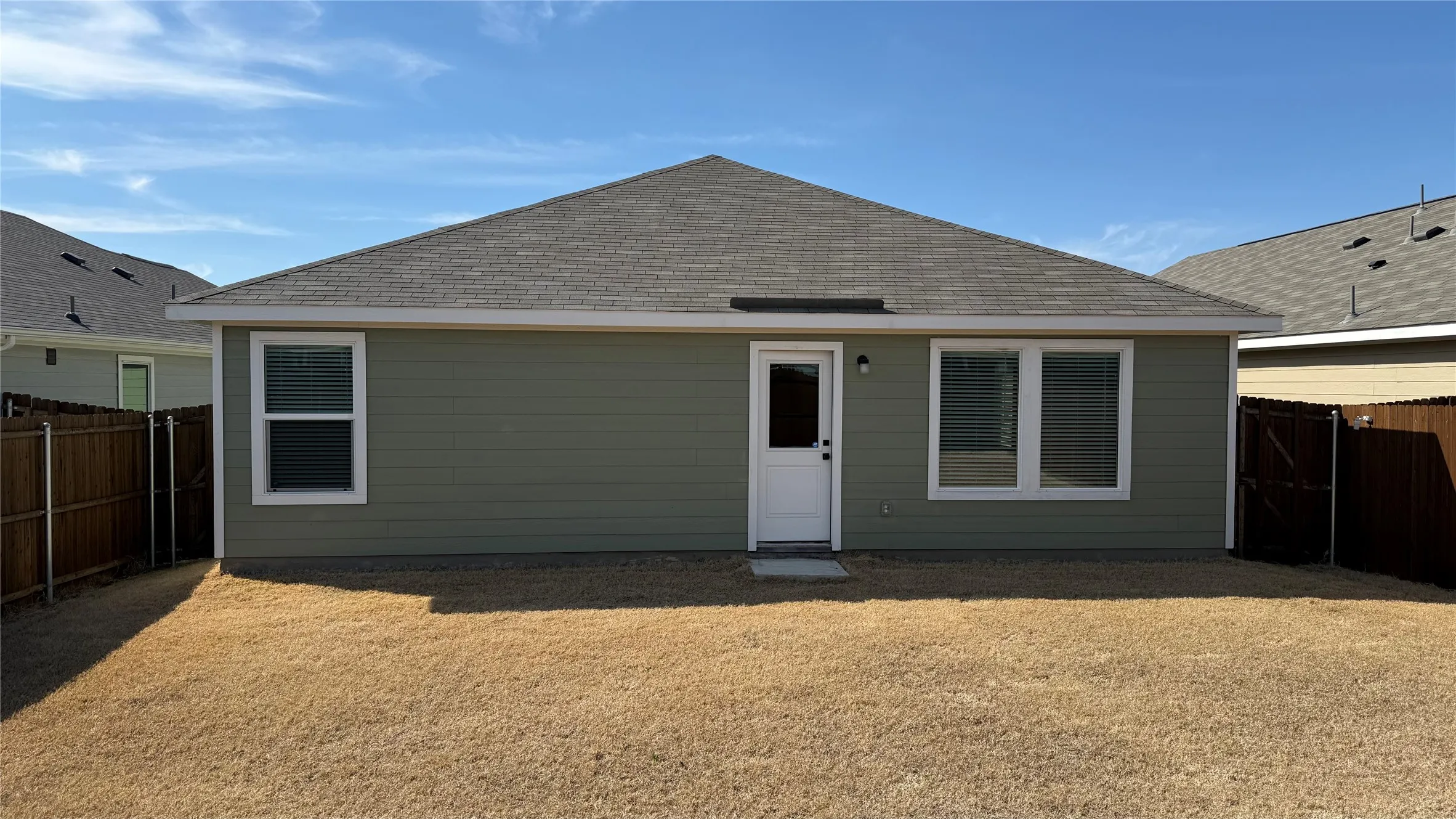 Single-story residence featuring a gray shingle roof, green siding, and white trim
