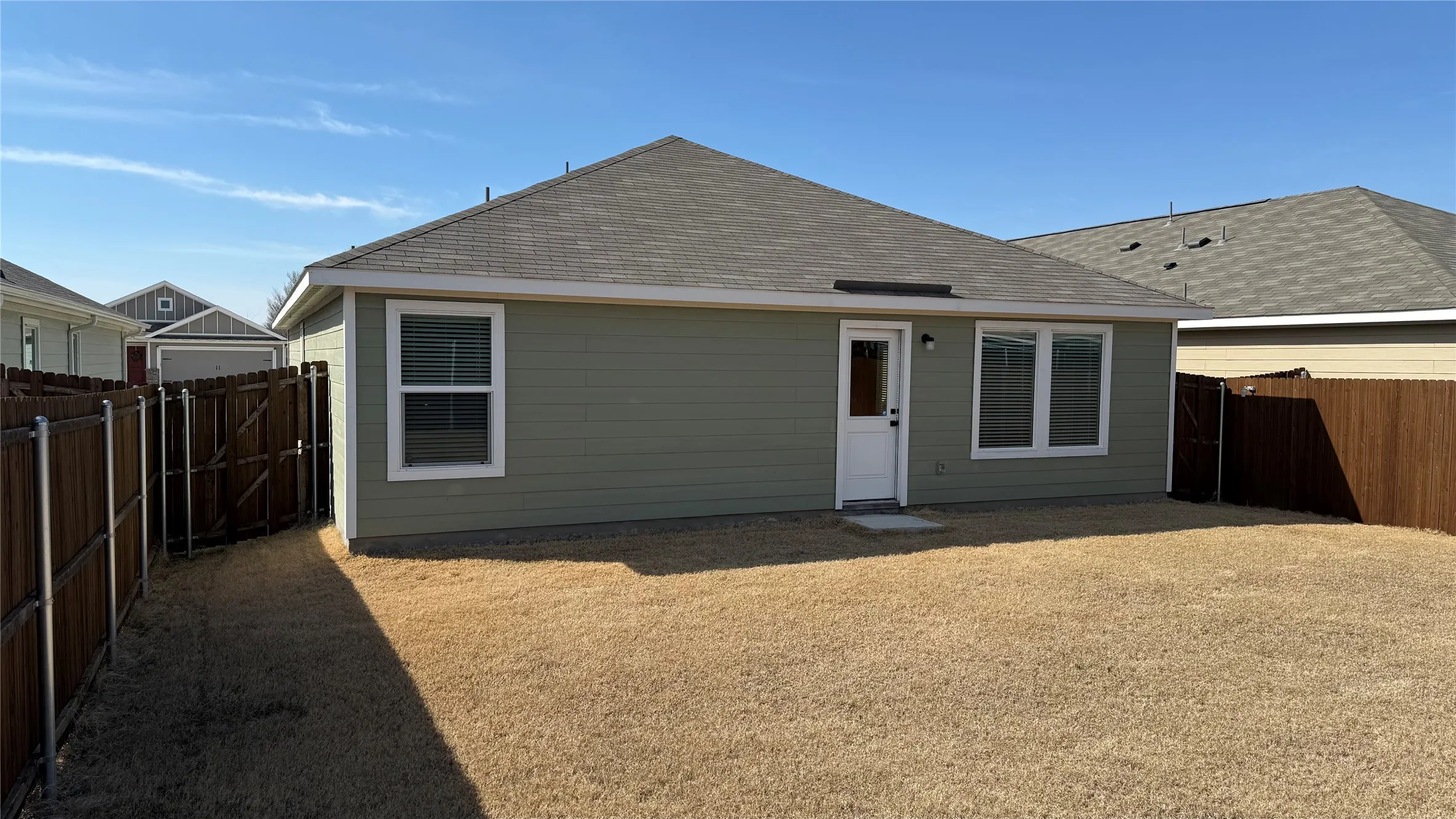 Rear exterior featuring horizontal siding, a private backyard, perimeter fencing, and a back entry door