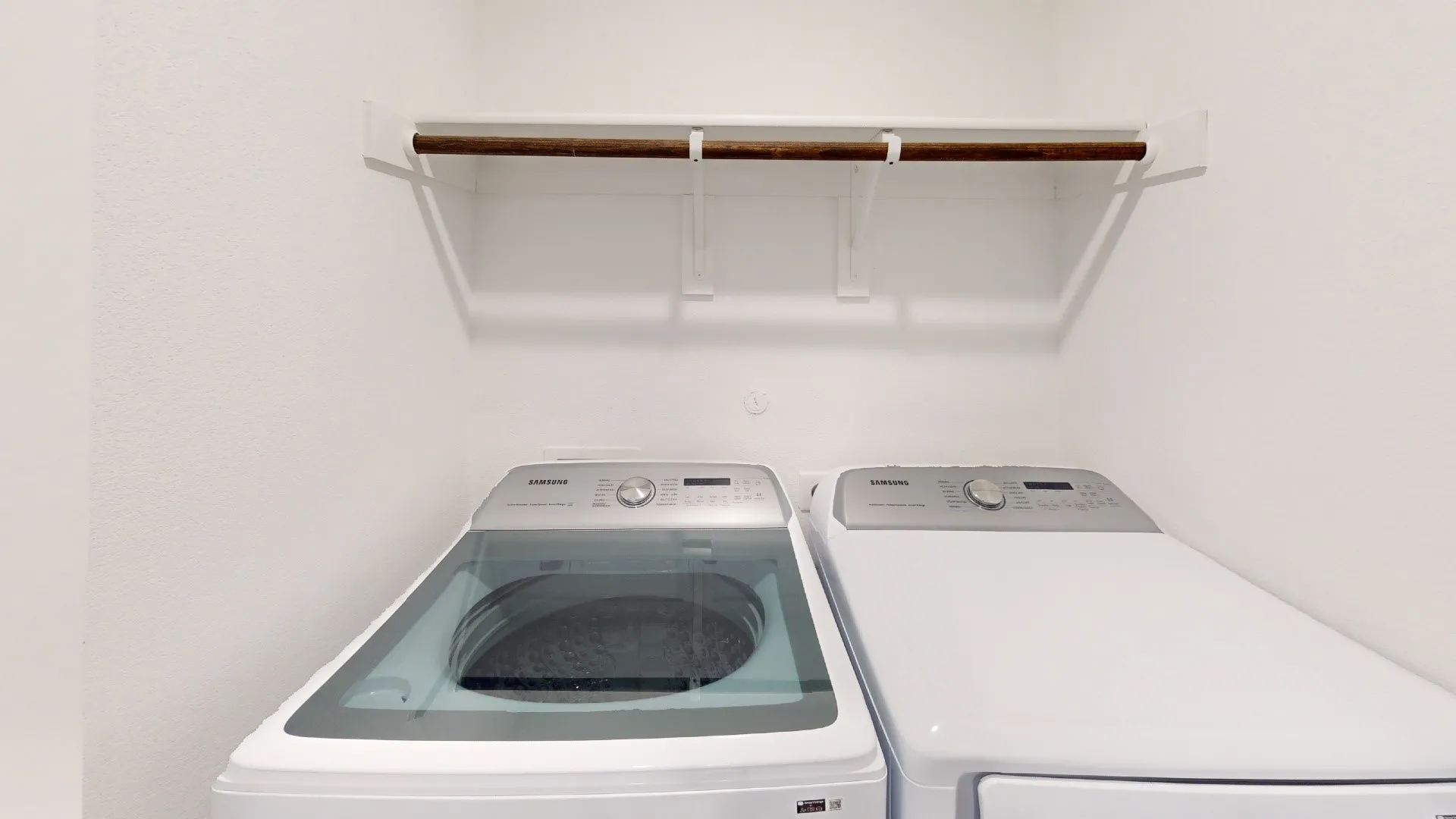 Laundry area featuring a built-in shelf and hanging rod