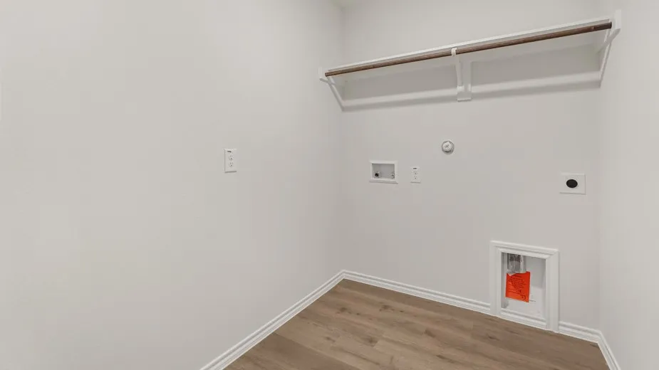 Dedicated utility space featuring wood-finish flooring, white walls, and a built-in hanging rod with shelving