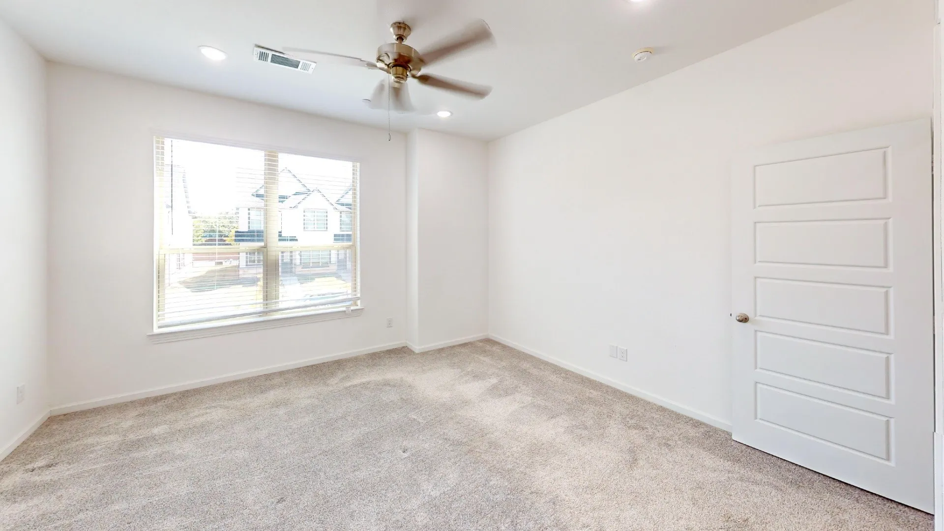 Carpeted room featuring a ceiling fan, recessed lighting, a window with blinds, and a paneled door