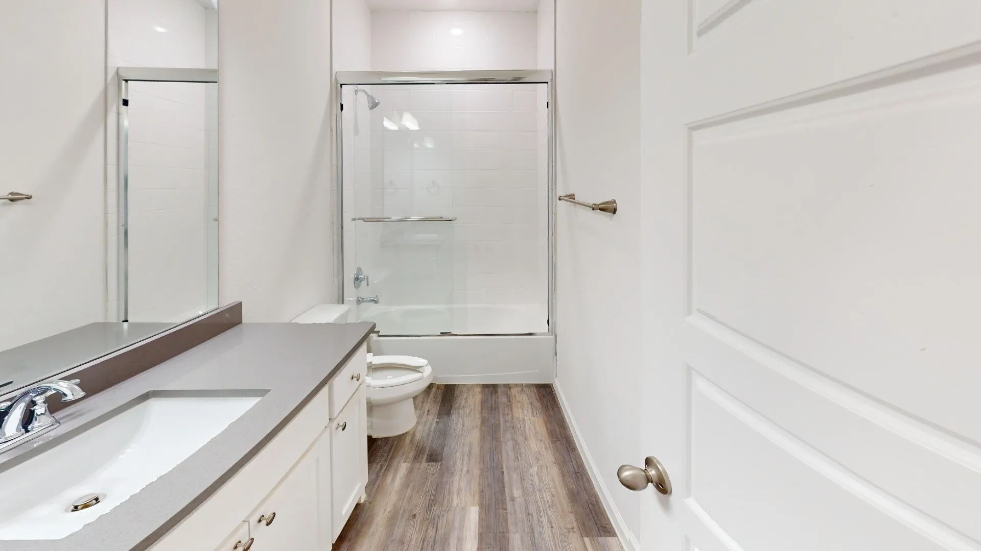 Vanity with integrated sink, chrome faucet, gray countertop, and white cabinetry