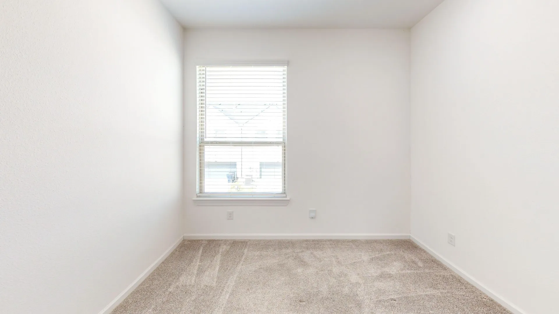 Neutral wall finishes, light-toned carpeting, and a window with blinds