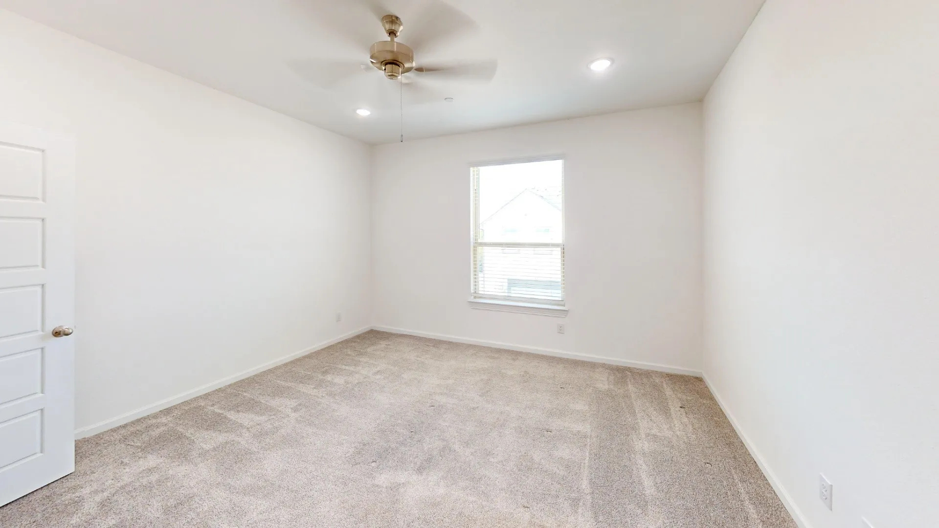 Neutral tone carpet, recessed ceiling lighting, ceiling fan, and a paneled door